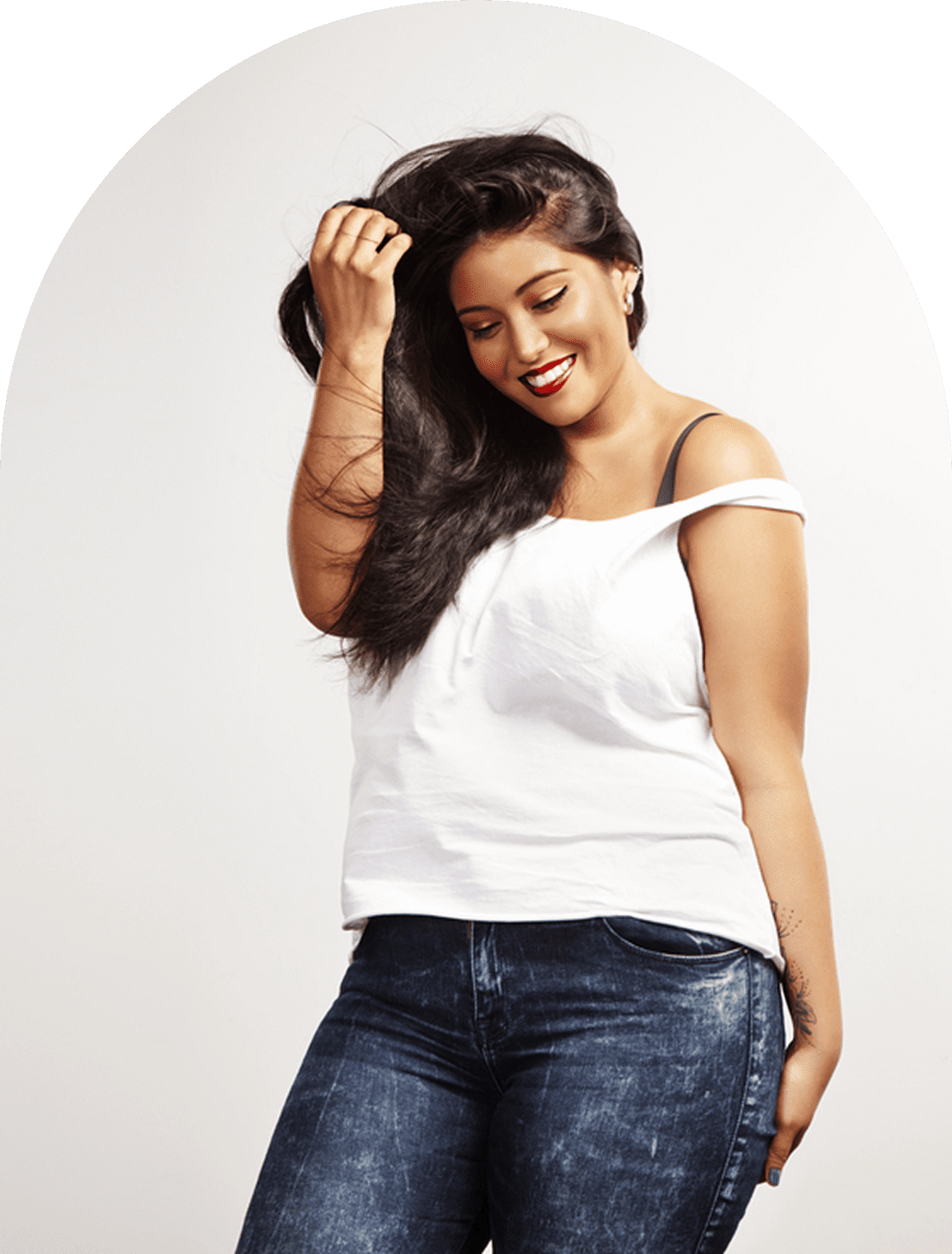 A smiling woman with long dark hair wearing a white top and jeans.