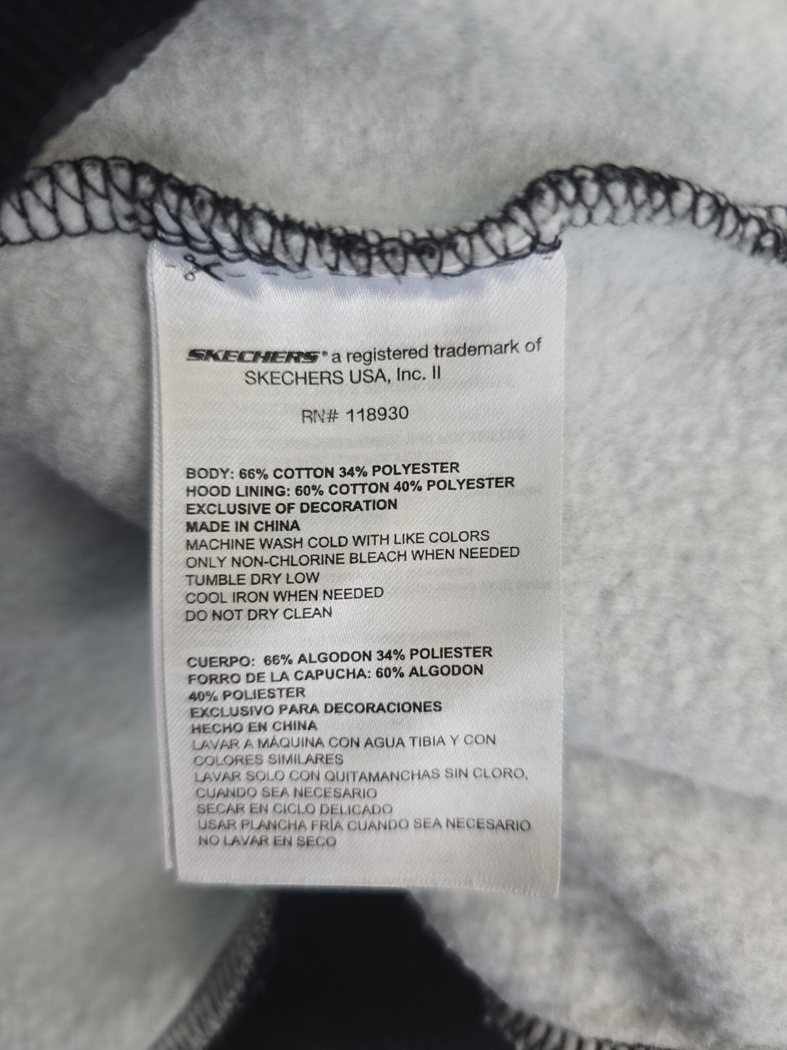 Close-up of Diane von Furstenberg x Skechers brand and 3XL size tag on black and white geometric hoodie