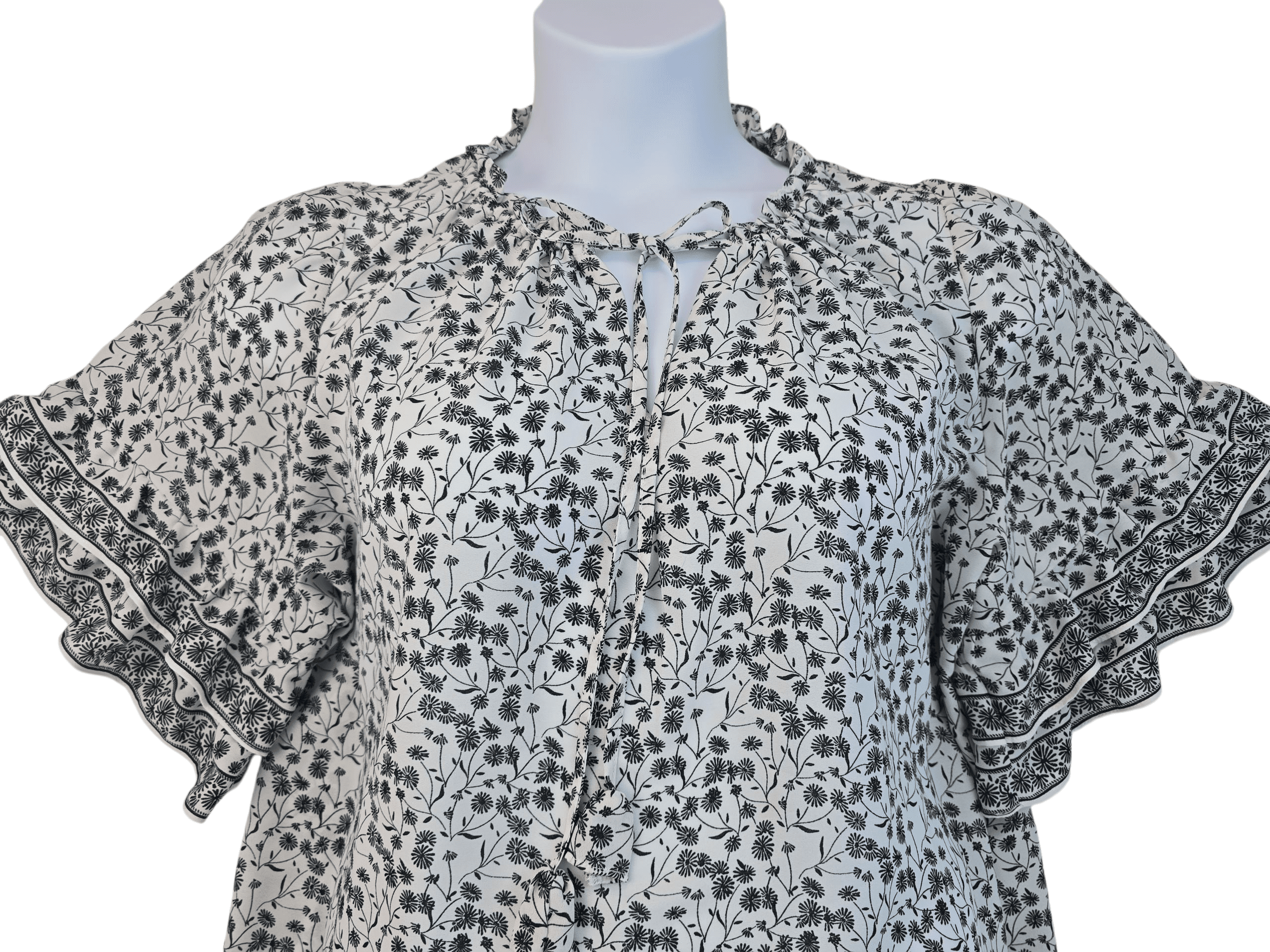 Light grey floral blouse with puffed sleeves and a tie neckline.