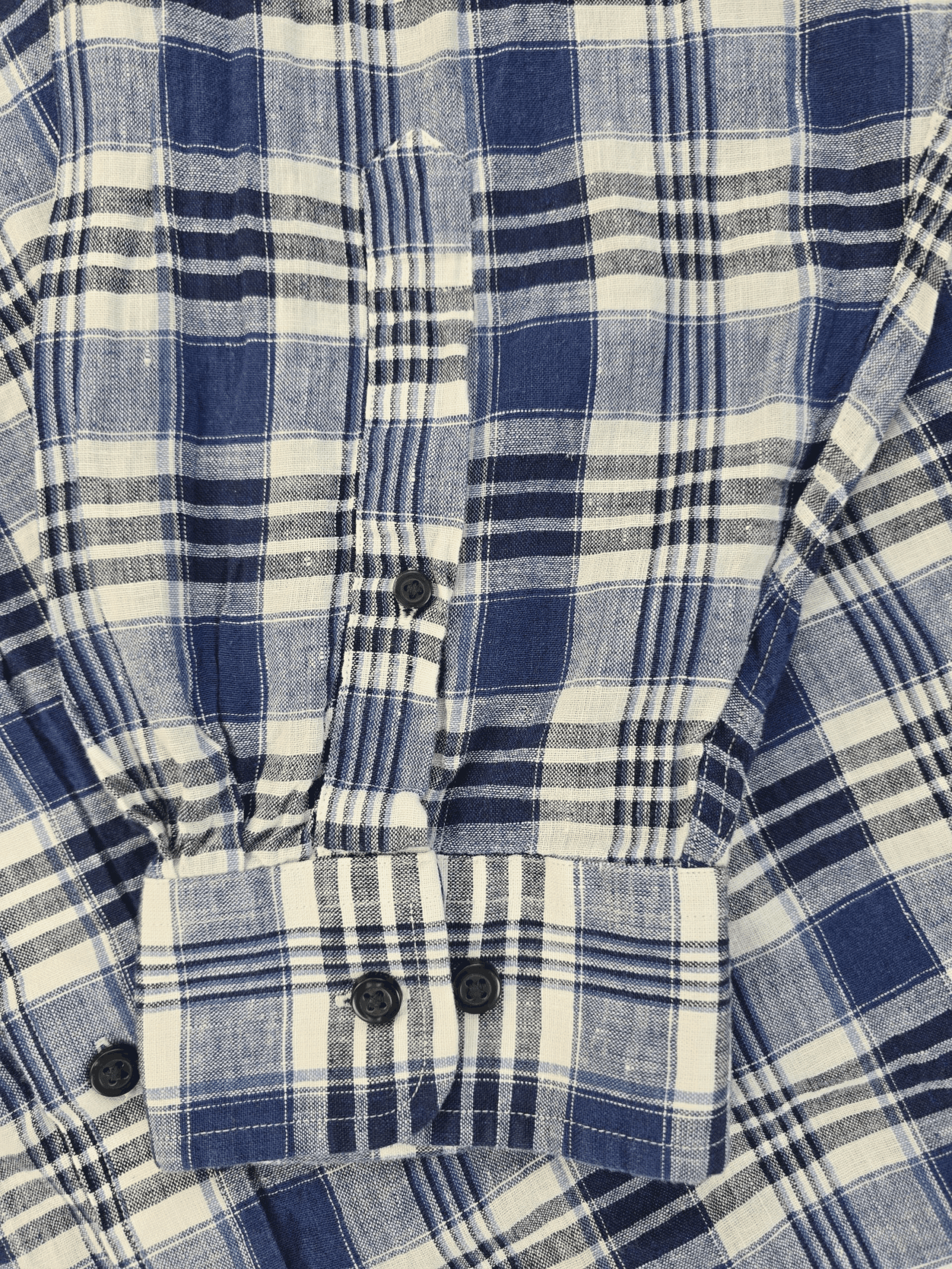Close-up of a blue and white plaid shirt cuff with buttons.