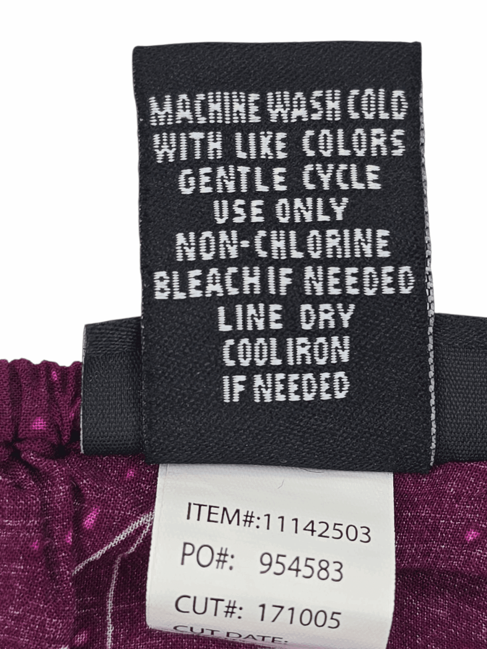 Clothing care label with washing and drying instructions on a purple fabric.