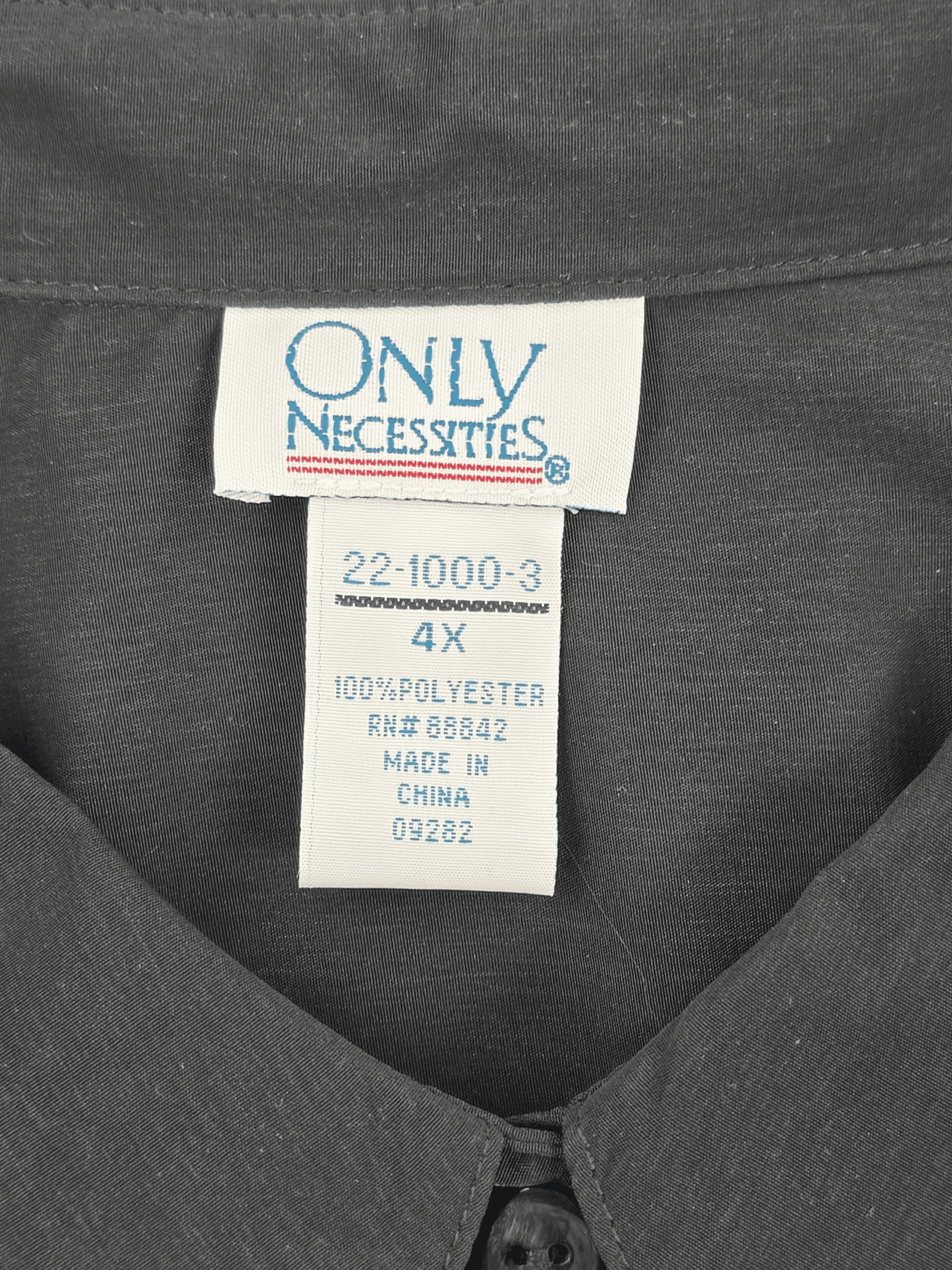 Only Necessities brand and size tag on black button-up shirt in women’s plus size 4X.