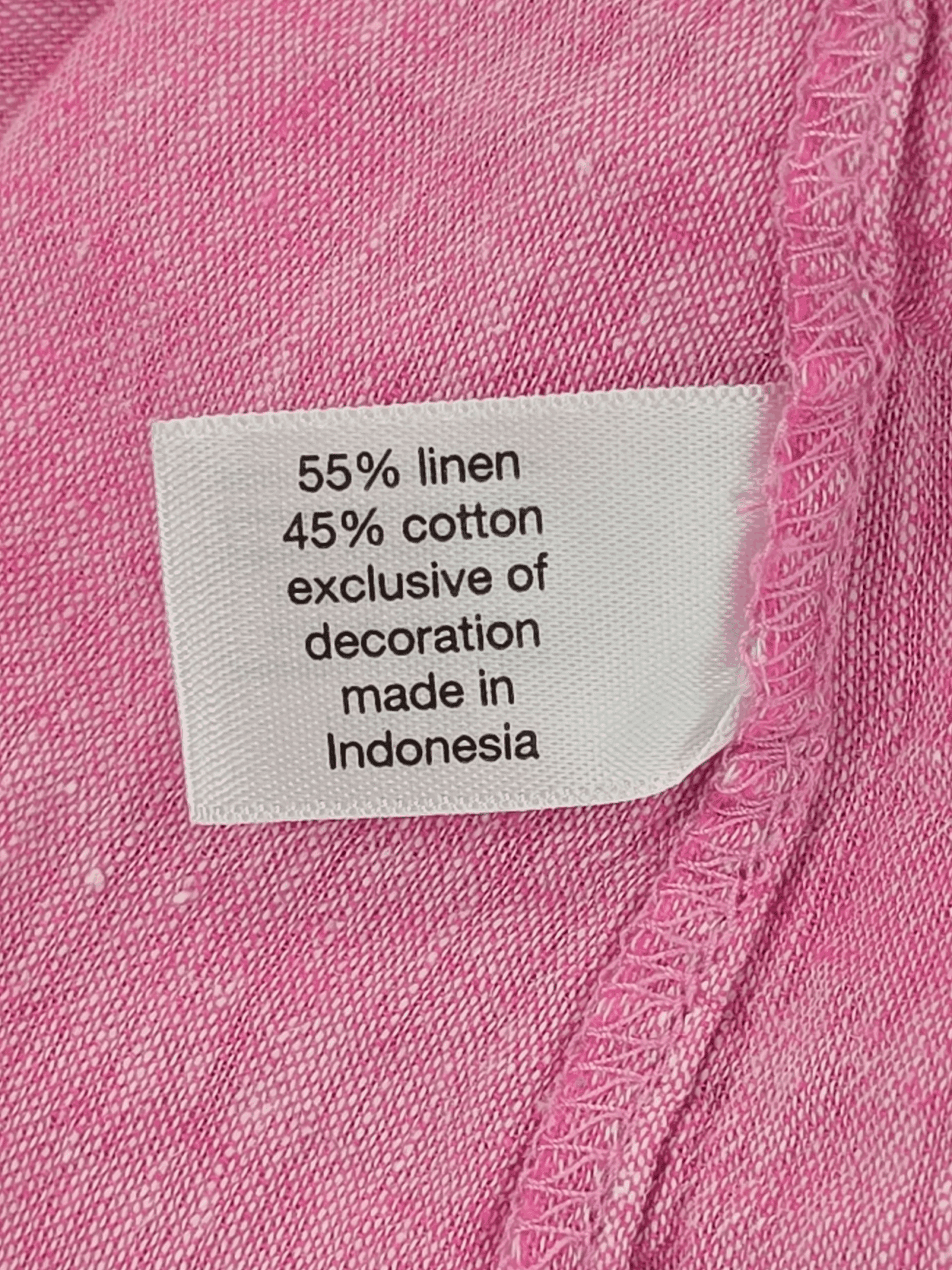 Material content tag listing linen and rayon blend for Lane Bryant pink flutter sleeve peplum top.