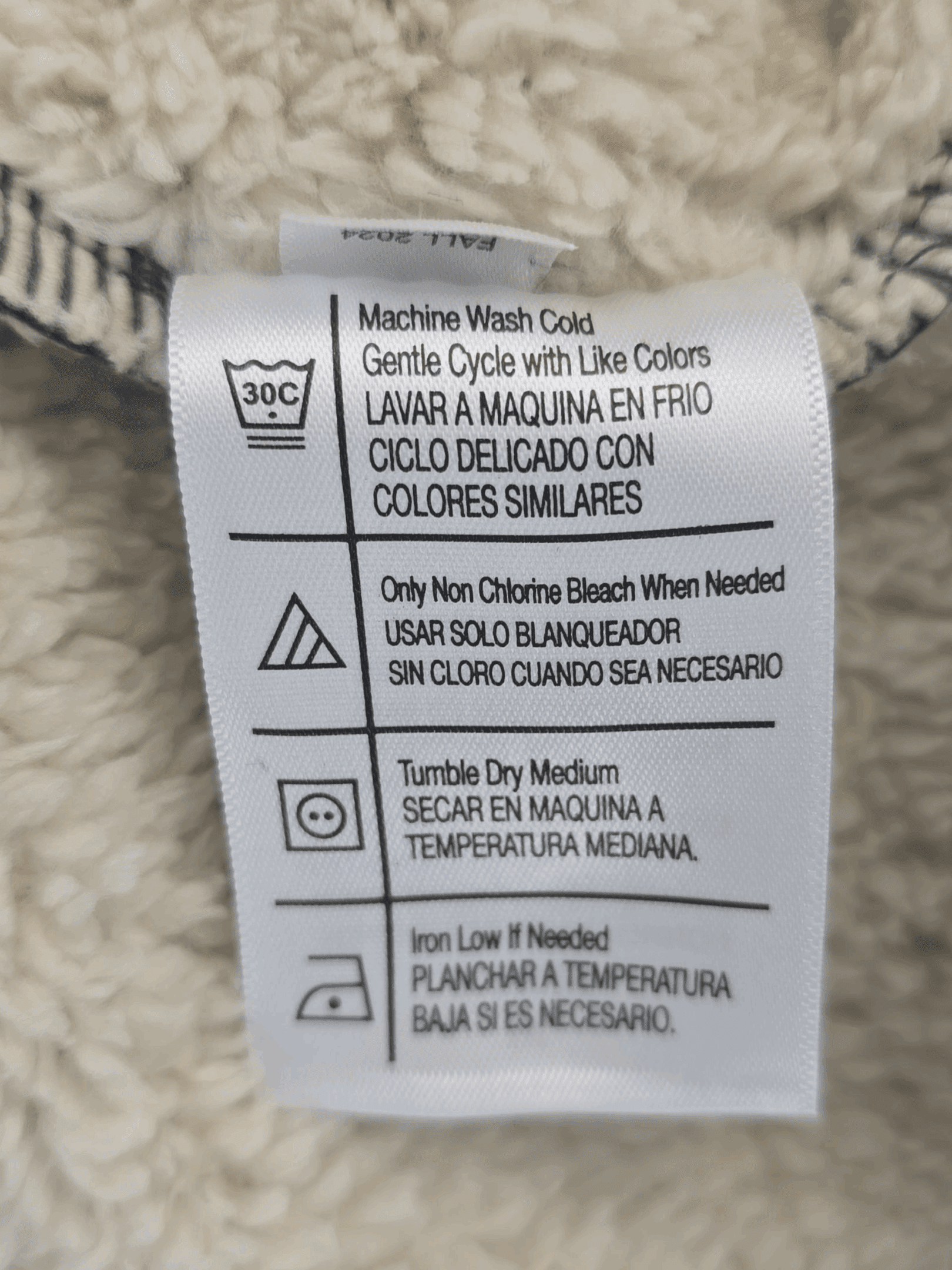 Clothing care label with washing instructions in Spanish and English.