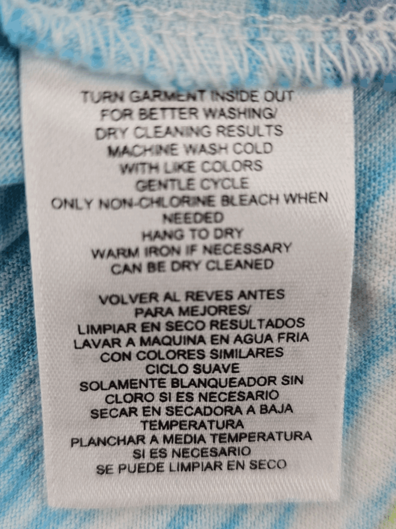 Garment care tag for Jones New York Sport Woman blue and yellow paint stroke pullover top showing washing and drying directions.