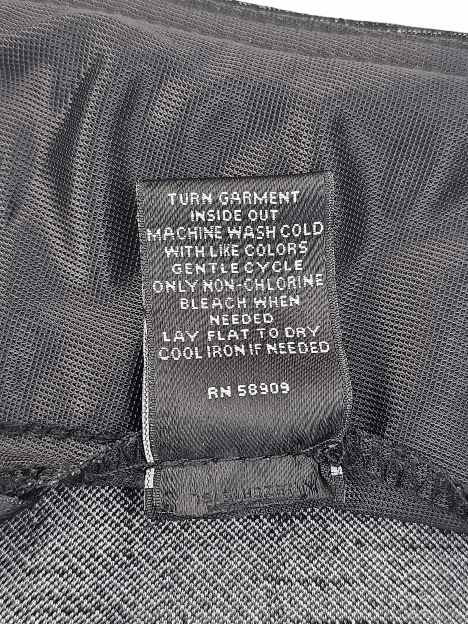 Clothing label with washing instructions inside a black garment pocket.