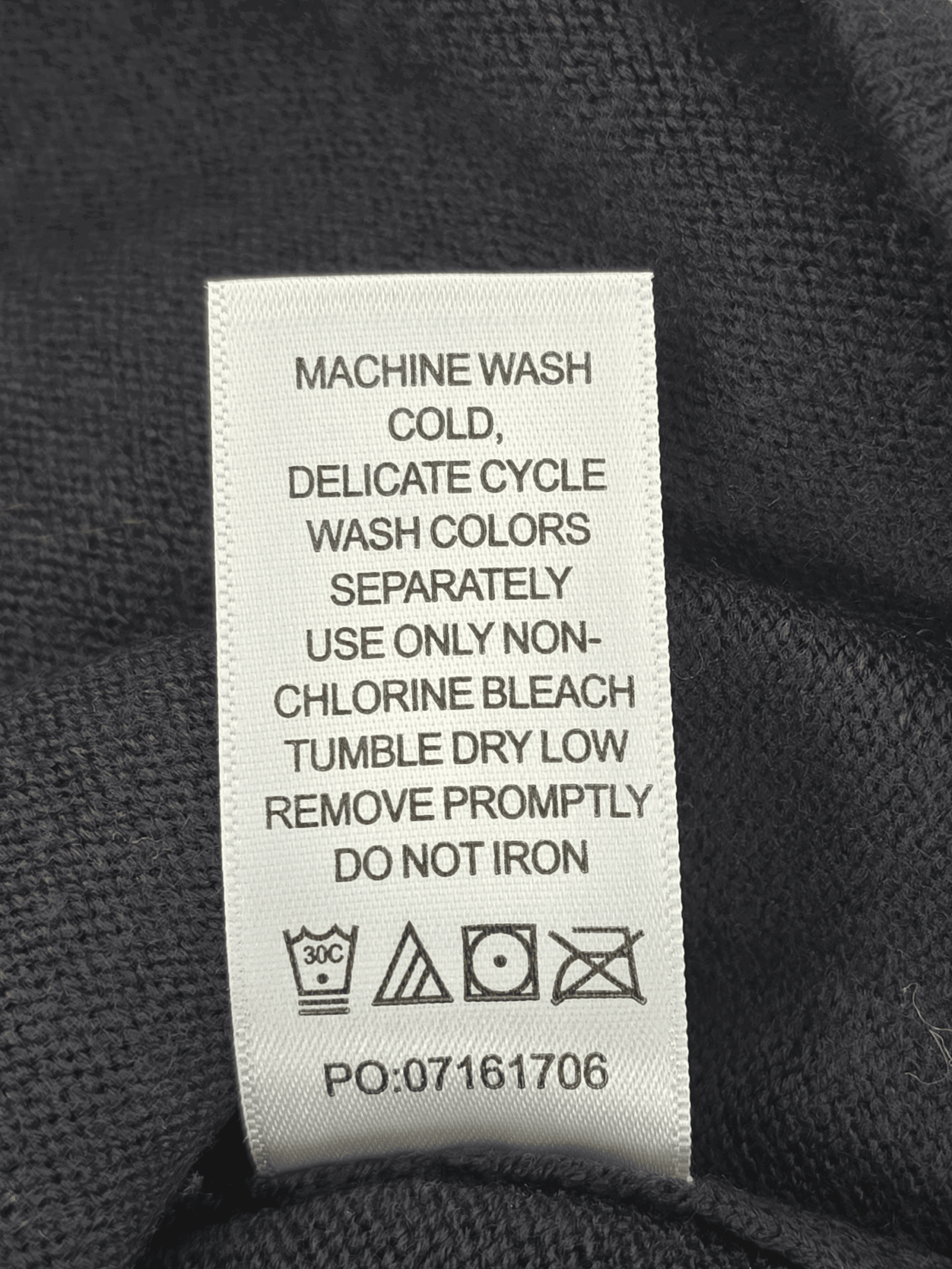 Clothing care label with washing and bleaching instructions.