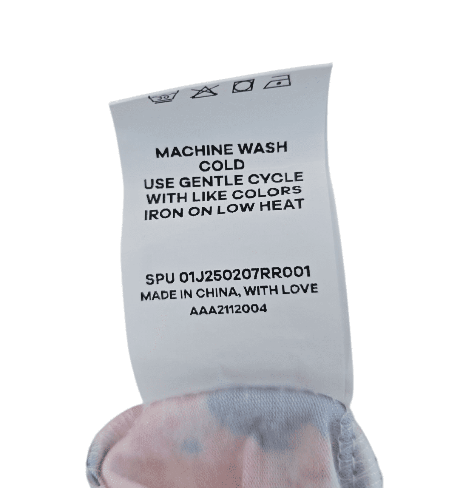 Garment care tag for Bloom Chic multi-color paint splatter V-neck pullover top showing washing and drying directions.