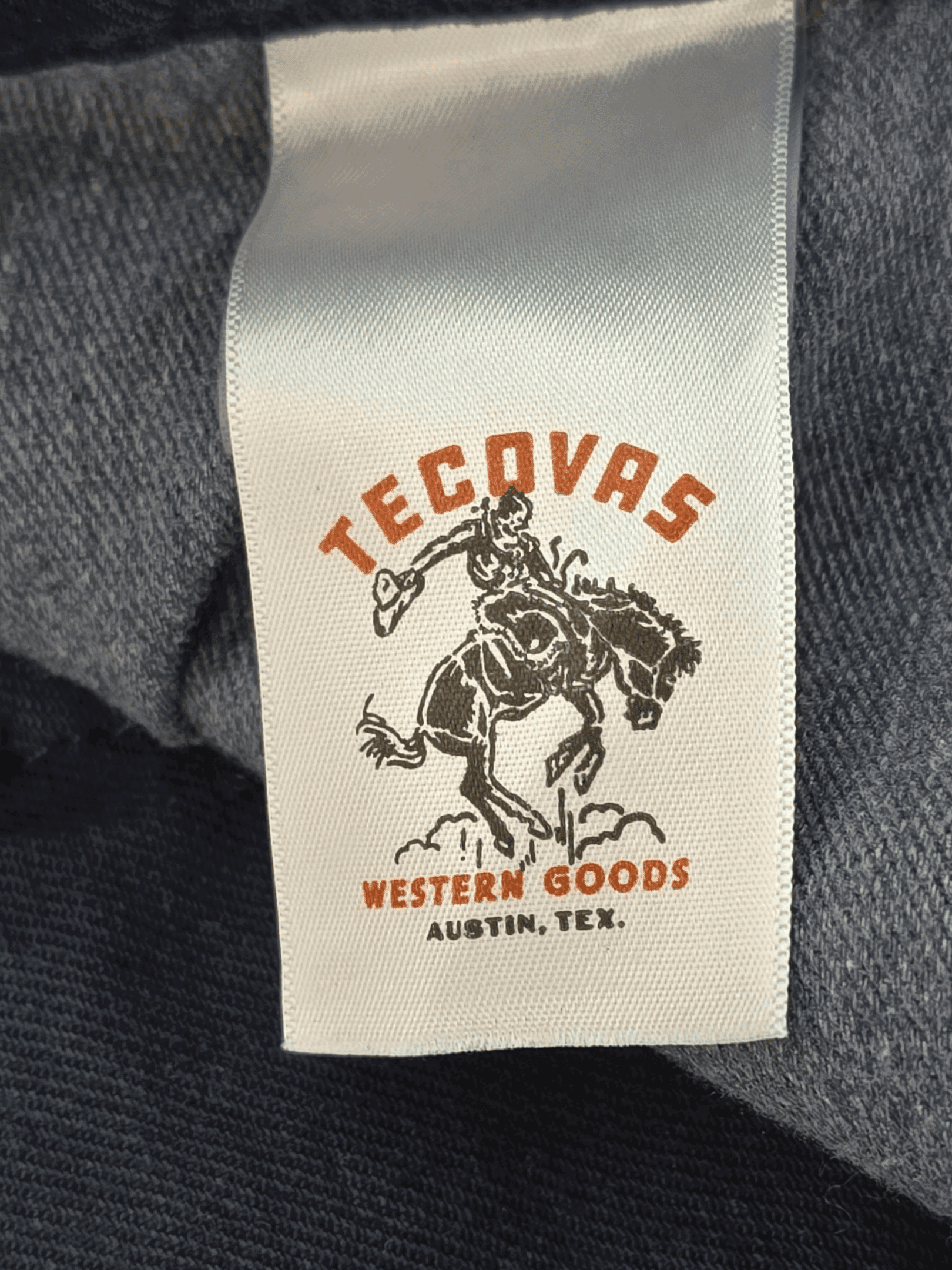 Tag showing a rodeo rider with 'Tecovas Western Goods' branding.