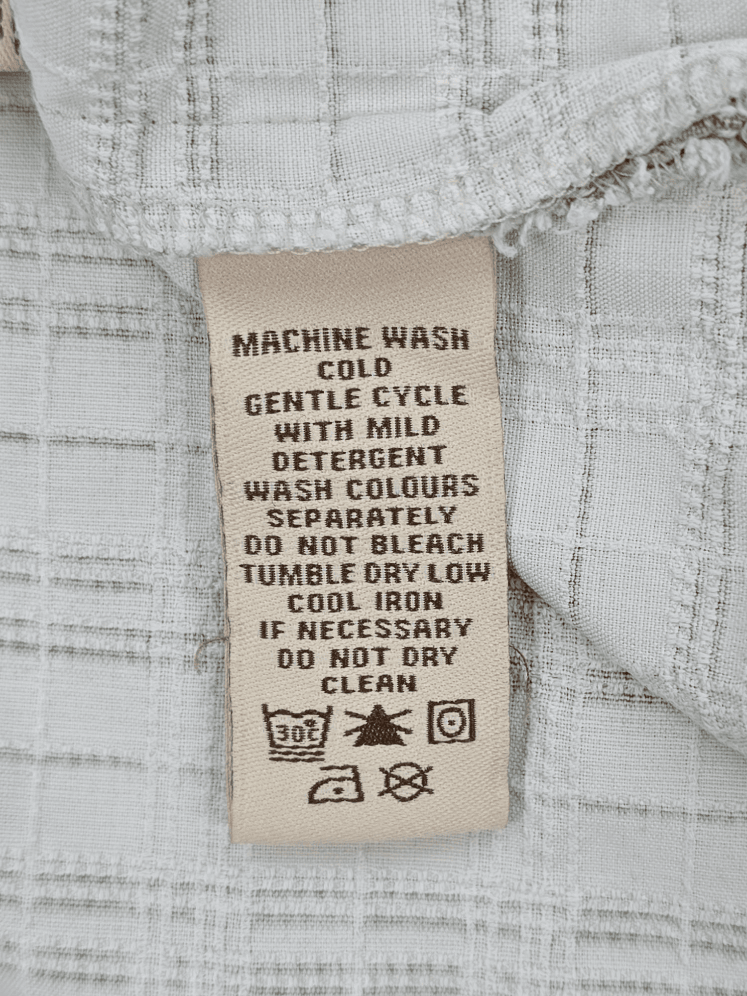 Garment care tag for Pusser’s Island Reserve tonal green checked silk cotton shirt showing washing and drying directions.