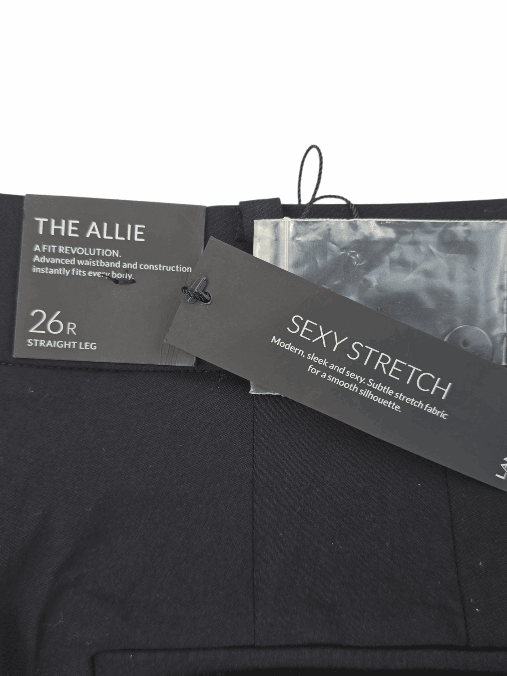 Close-up of two clothing tags labeled 'THE ALLIE' and 'SEXY STRETCH' on a black garment.