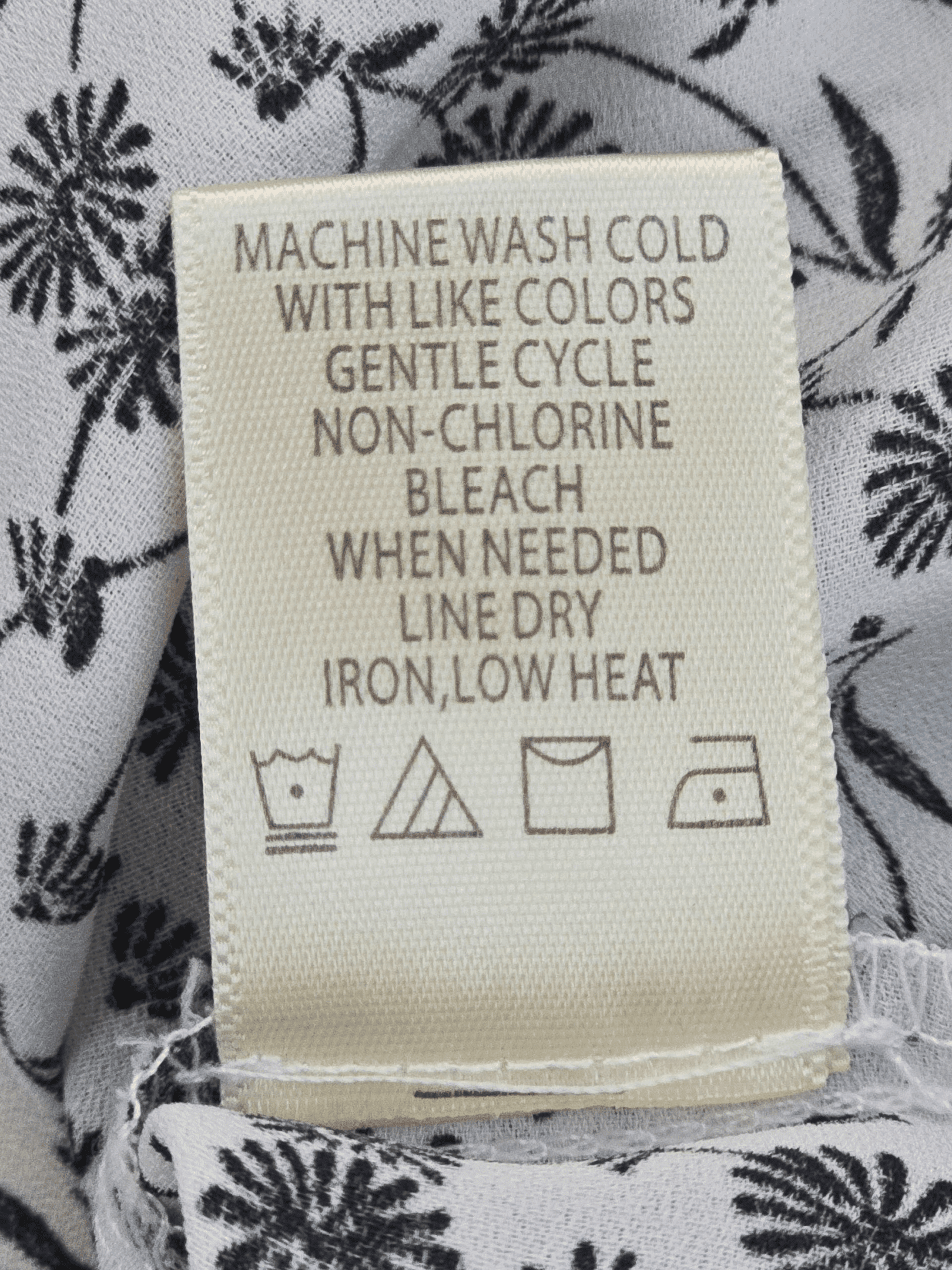 Clothing care label with washing and ironing instructions.