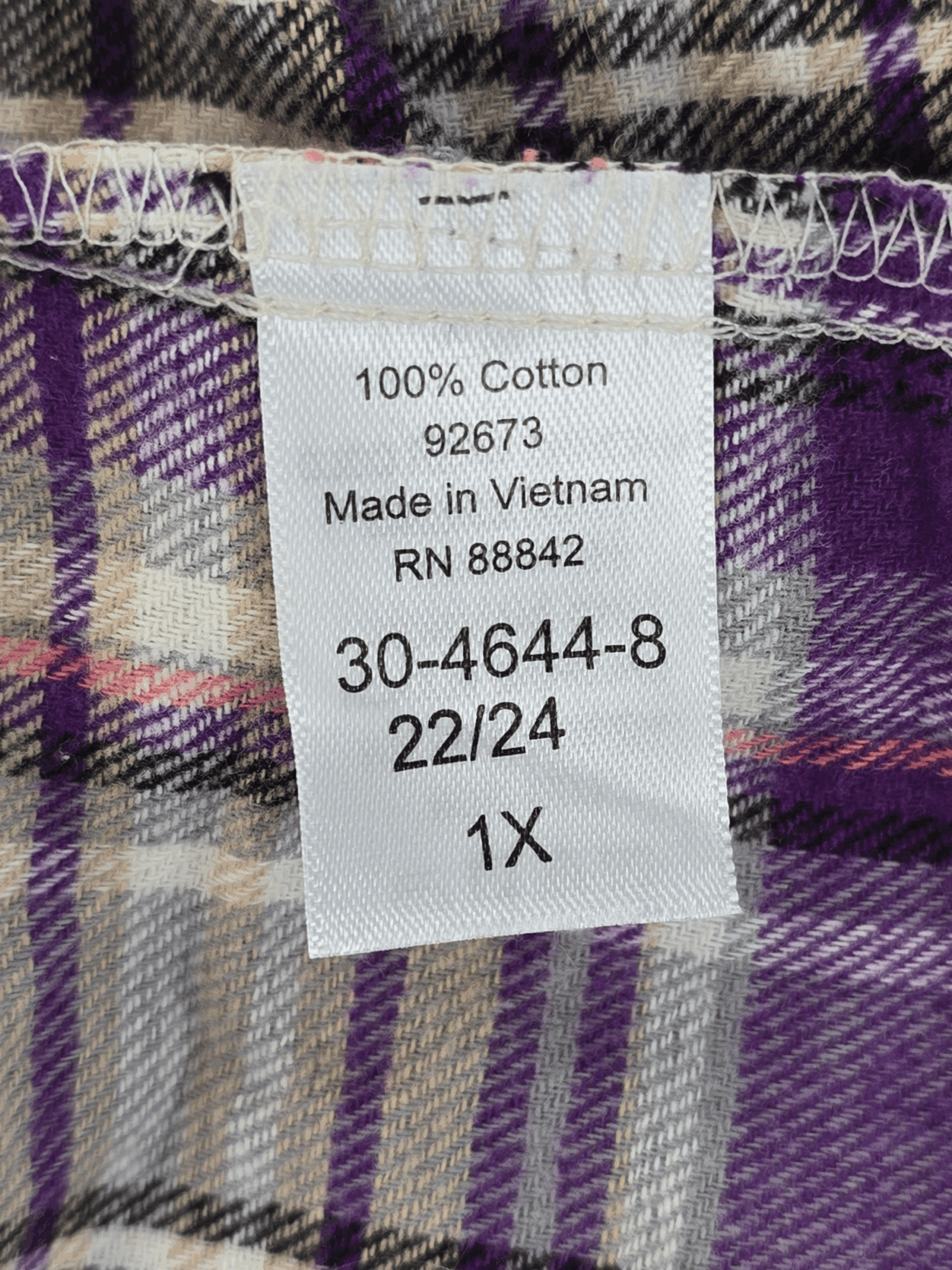 Material content tag listing 100% cotton for Woman Within purple and pink plaid flannel button-up shirt.
