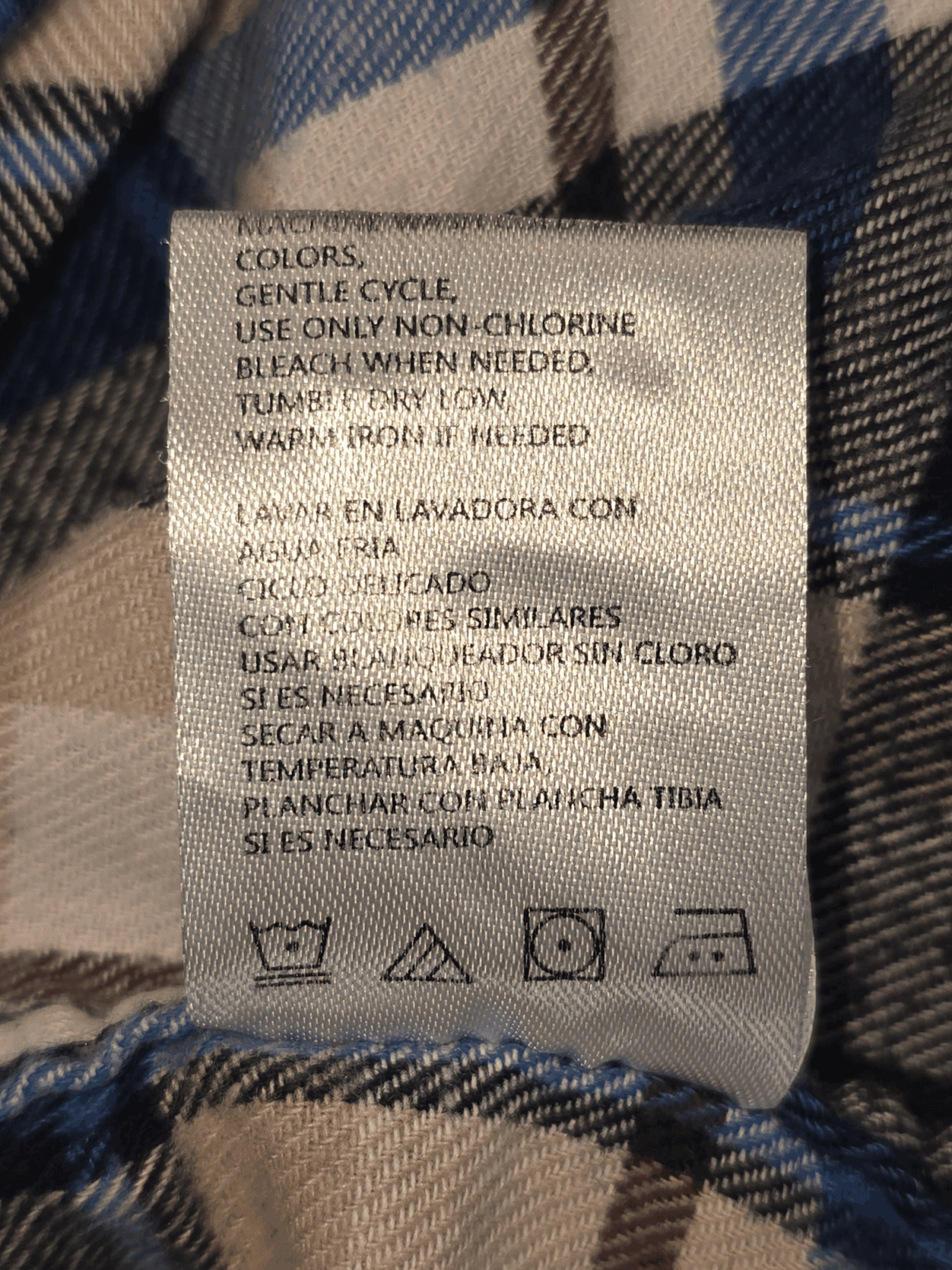 Clothing care label with washing and ironing instructions in Spanish.