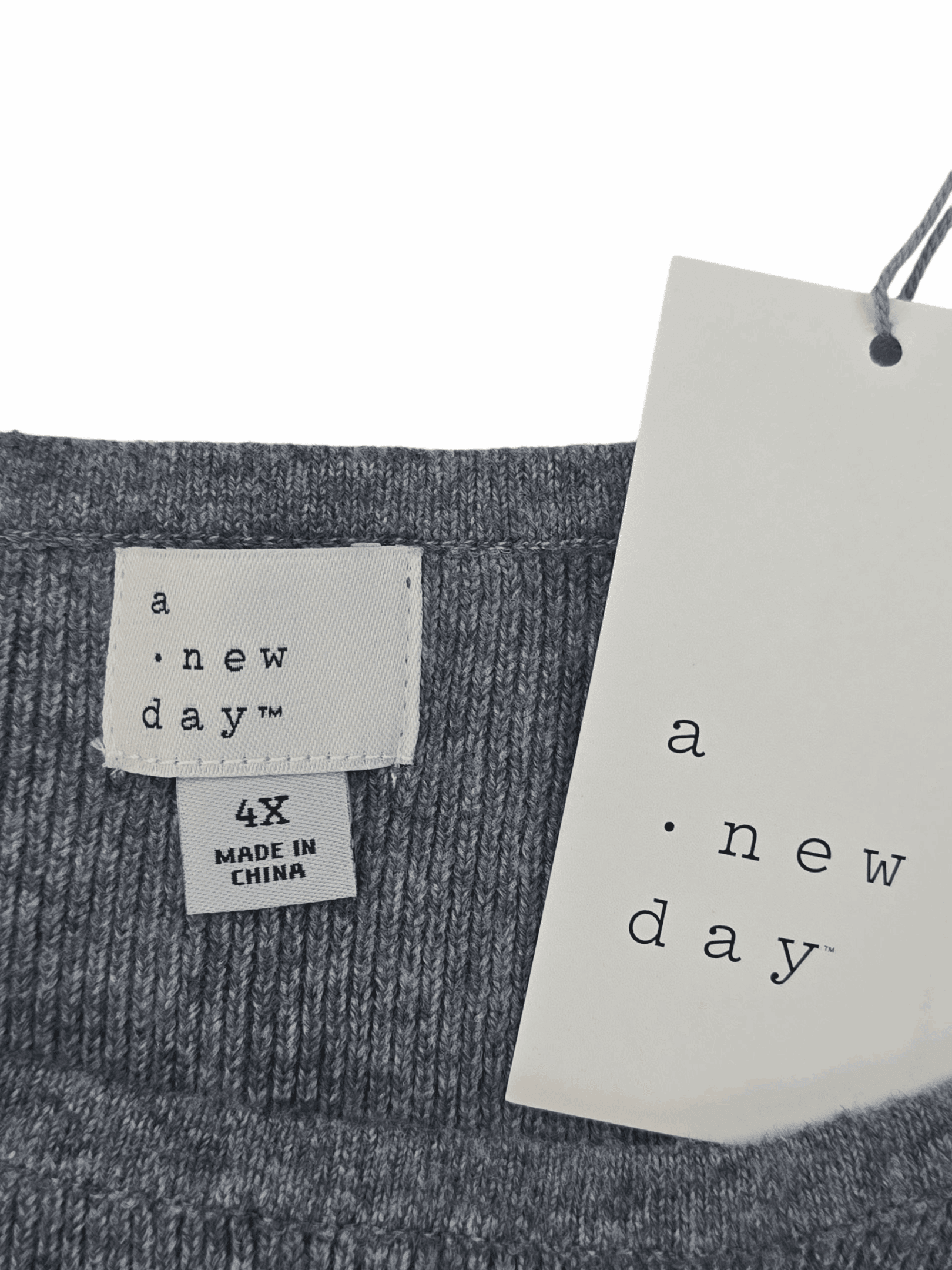 Clothing labels showing brand and size details on a gray garment.