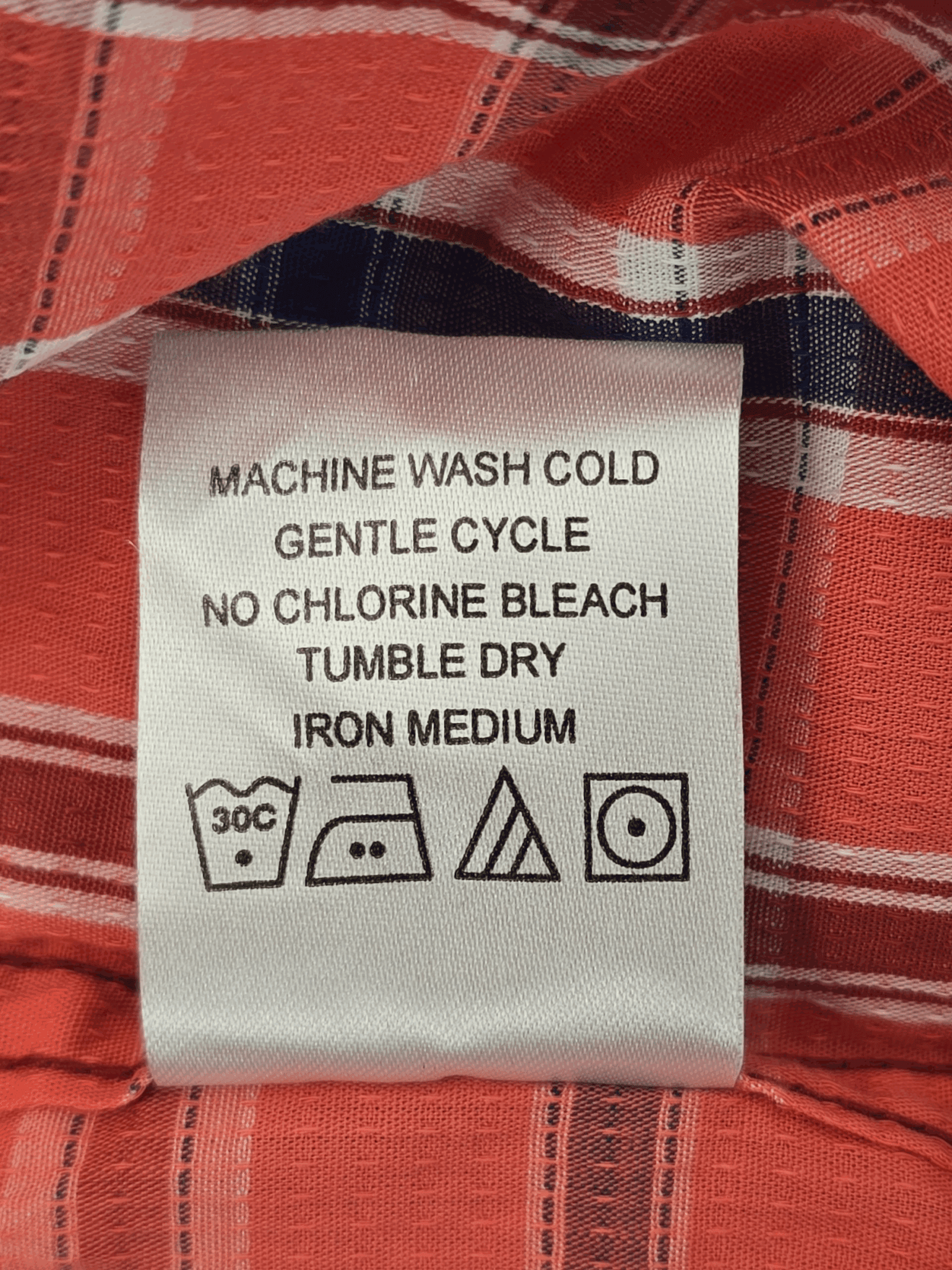 Clothing care label with washing and ironing instructions.