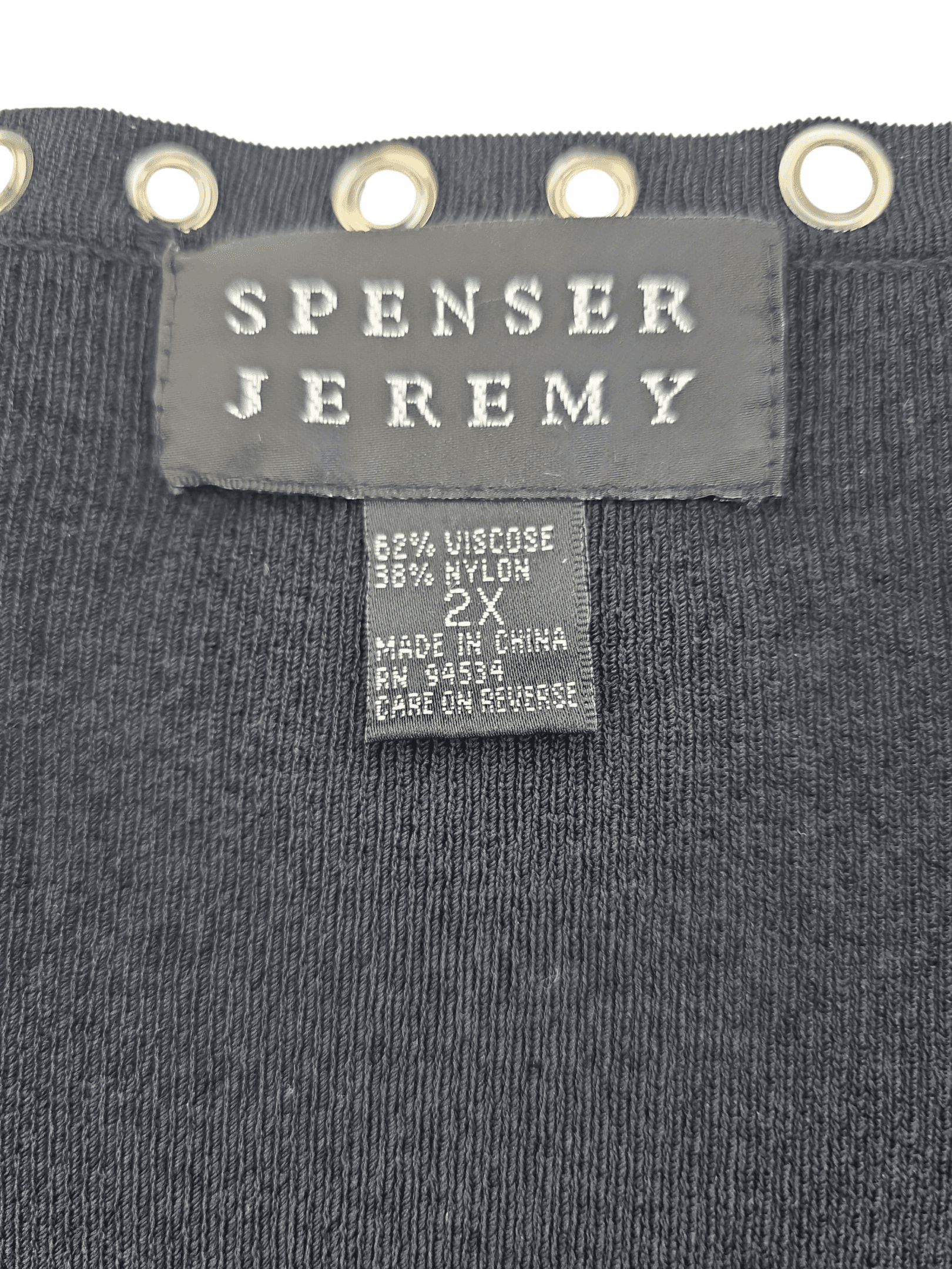 Close-up of a Spenser Jeremy clothing label on a gray garment.