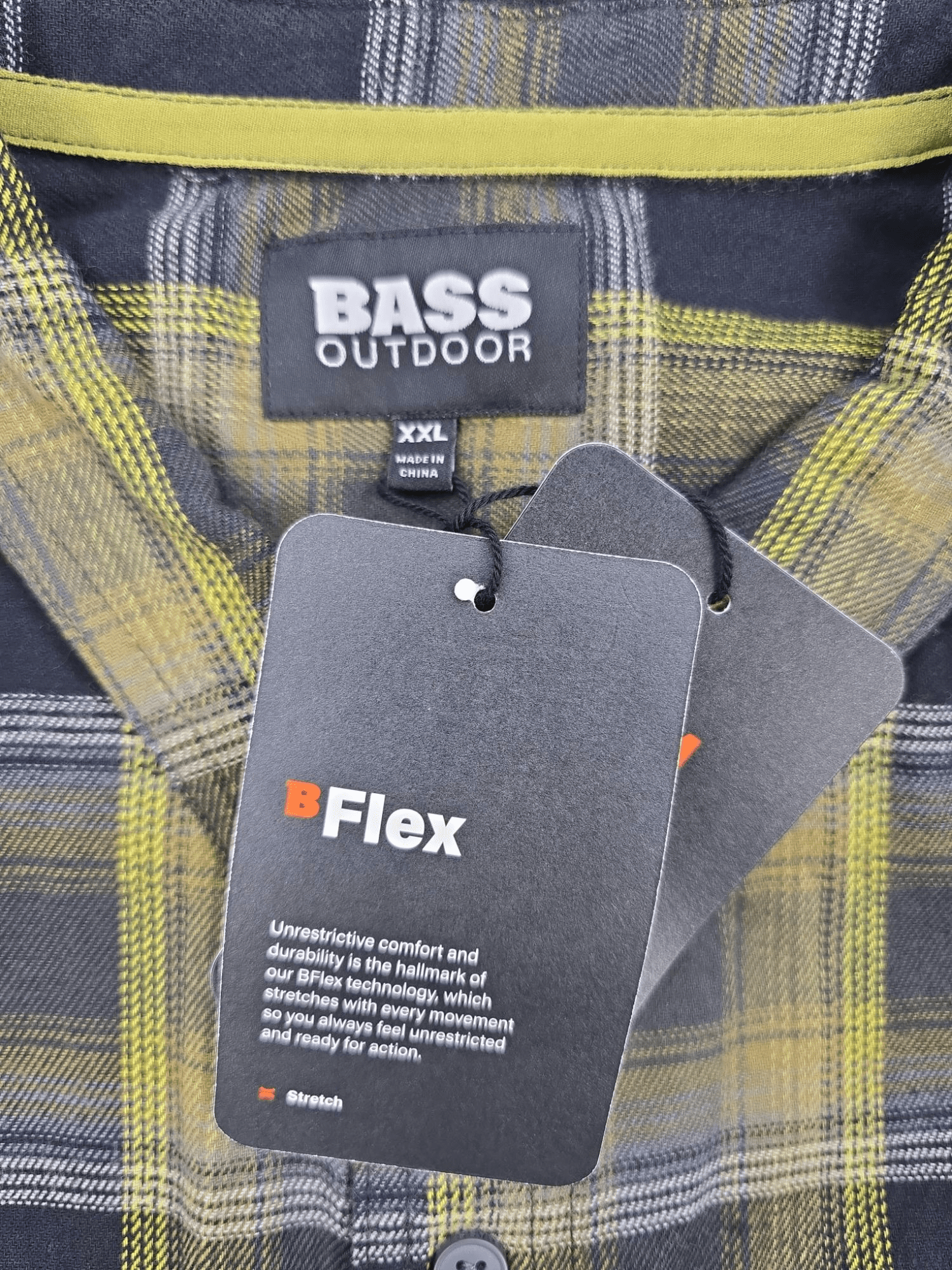 Bass Outdoor brand and size tag on green and black plaid flannel shirt in men’s size 2XL.