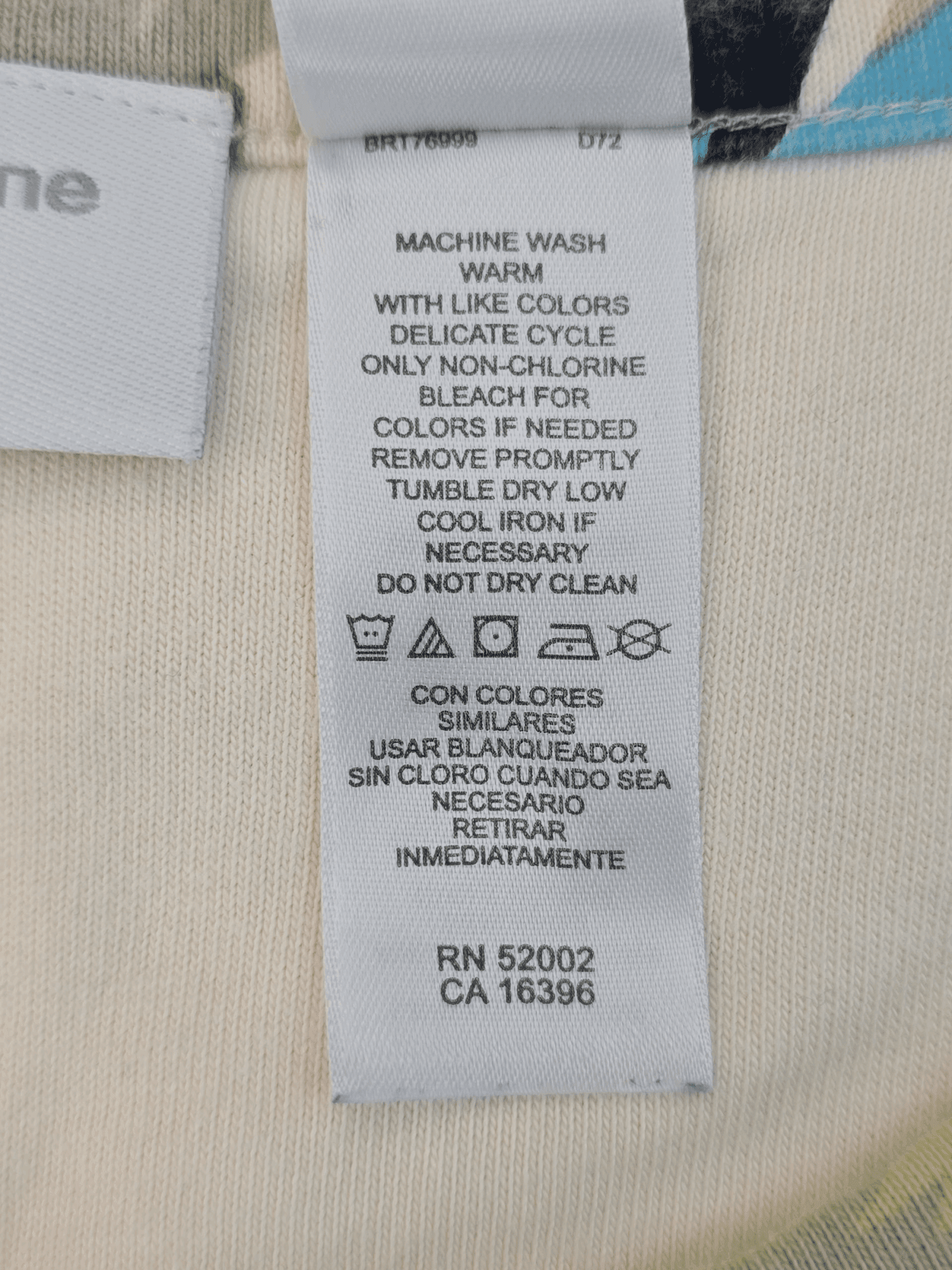 Clothing care label with washing and drying instructions in English and Spanish.