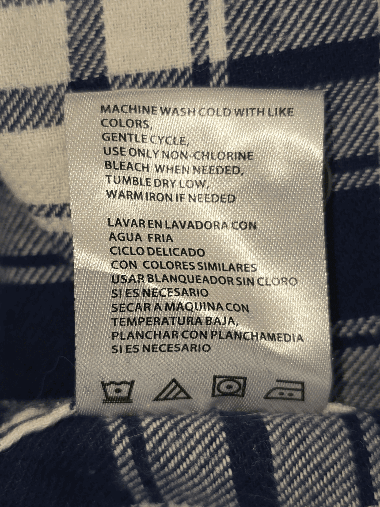 Clothing care label with washing and ironing instructions in multiple languages.