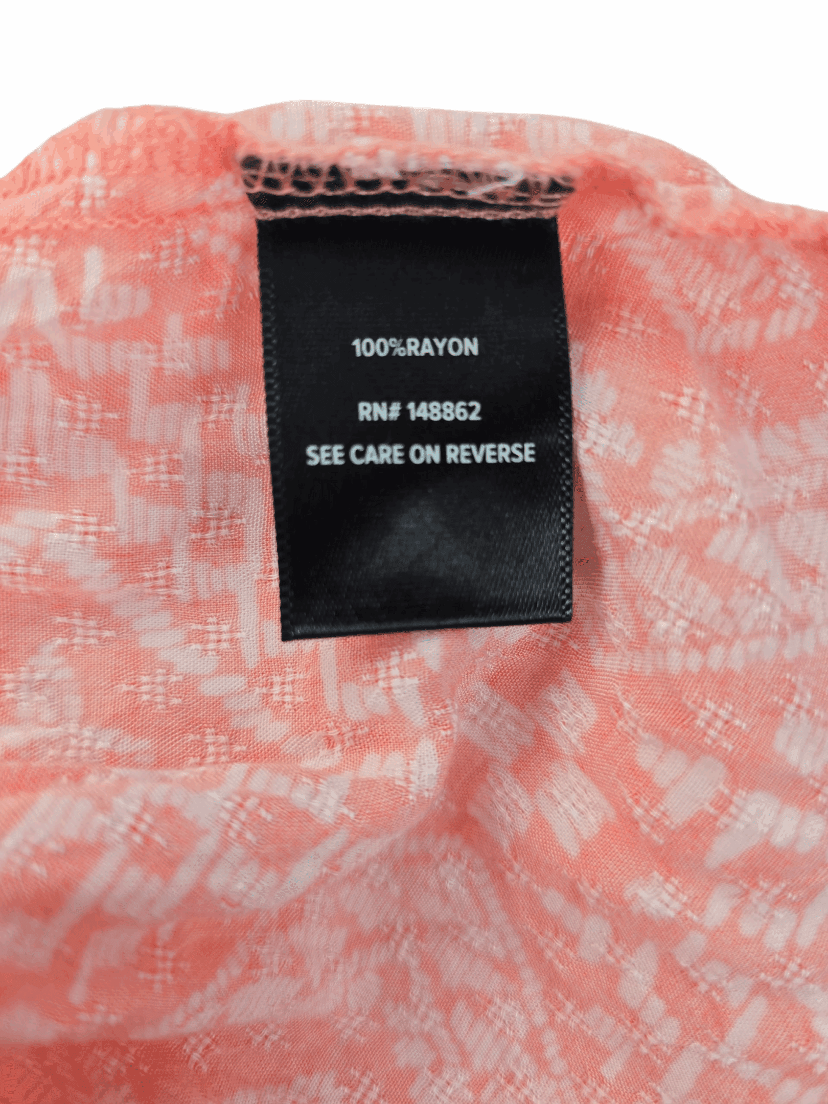 Clothing label with washing instructions and brand details.