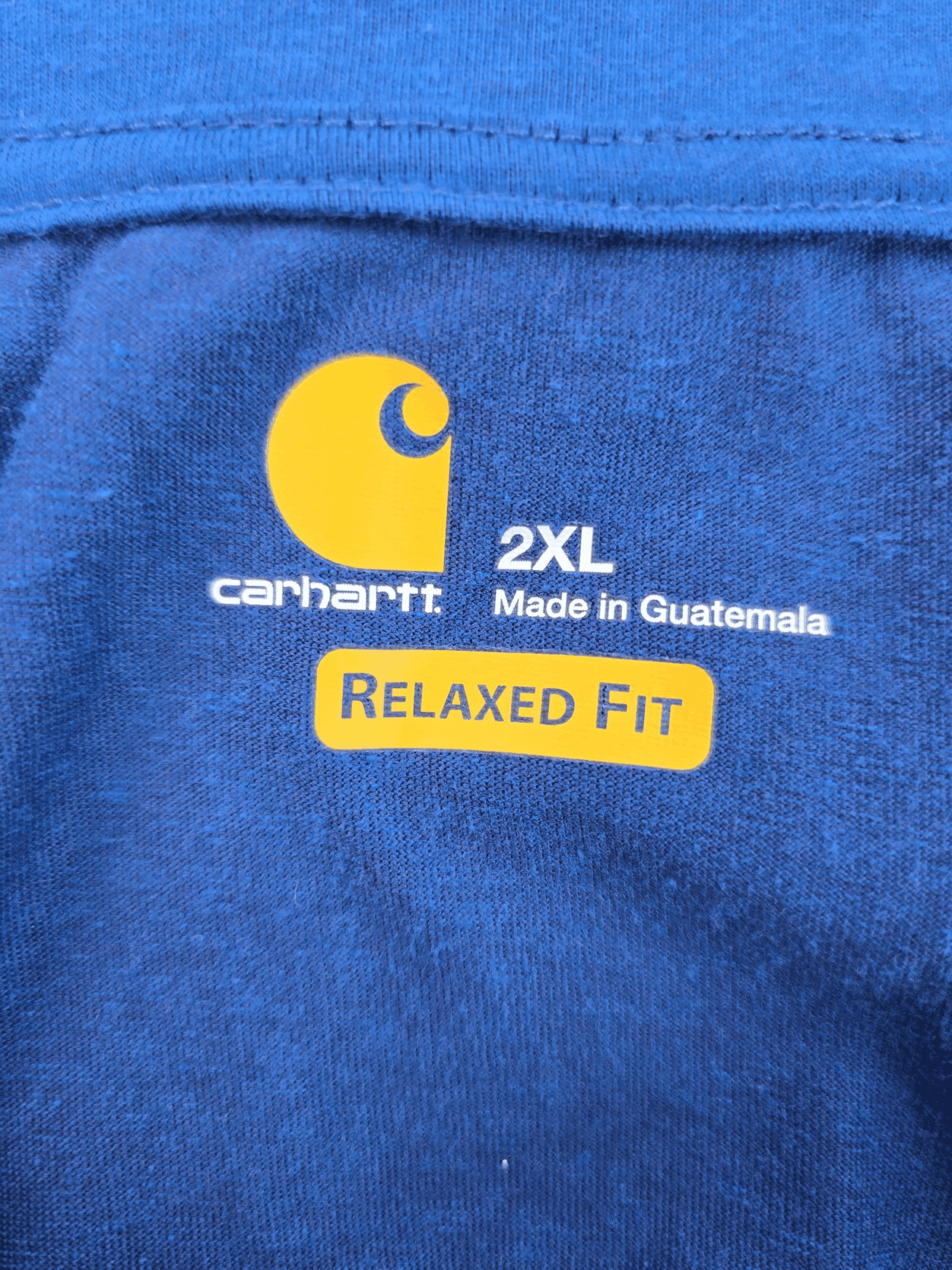 Close-up of a blue Carhartt t-shirt label showing size 2XL and relaxed fit.