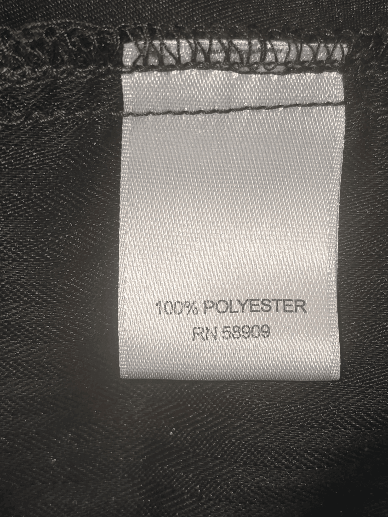 A clothing tag showing fabric content as 100% polyester.