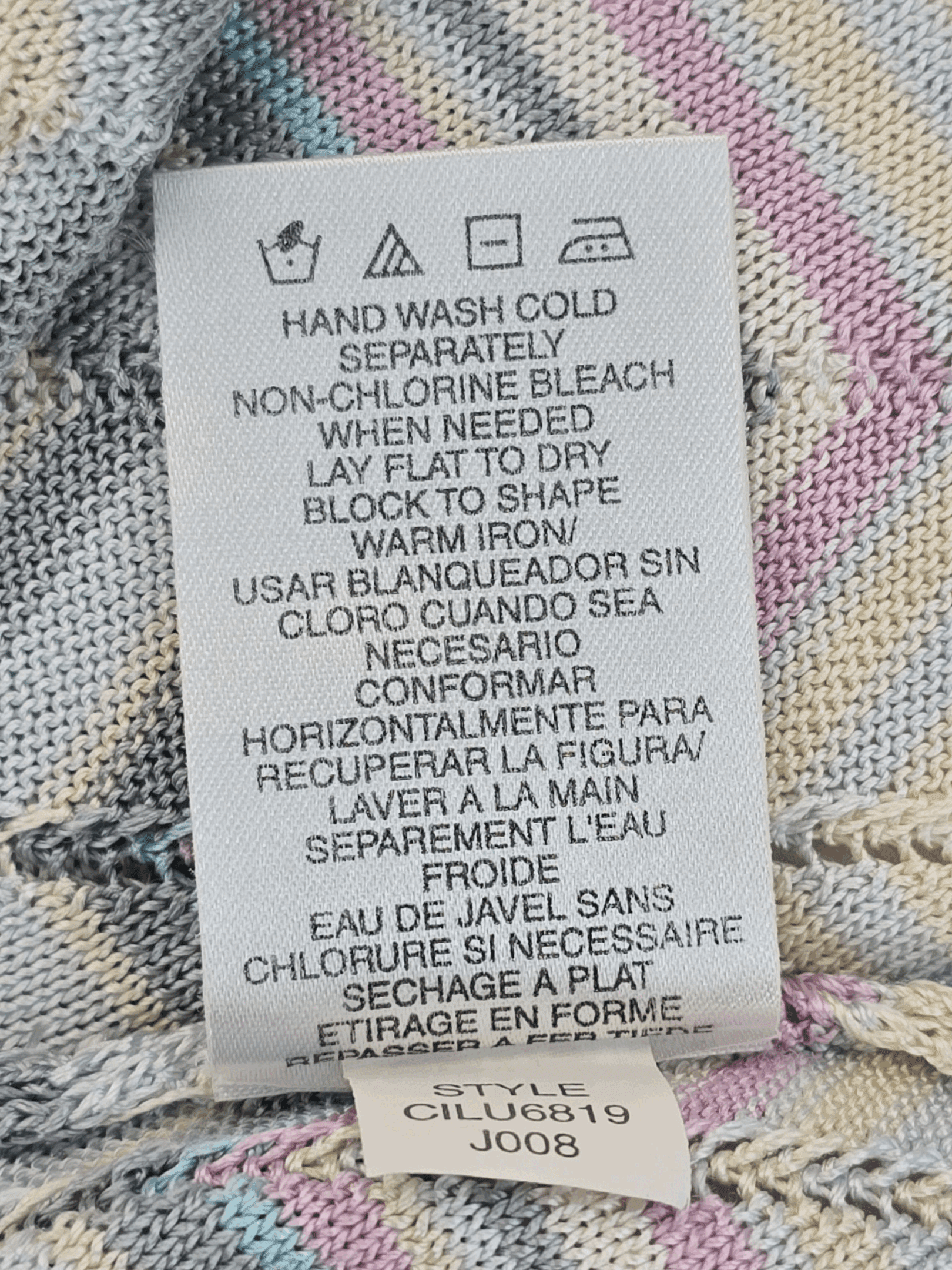 Clothing care label with washing and ironing instructions in multiple languages.