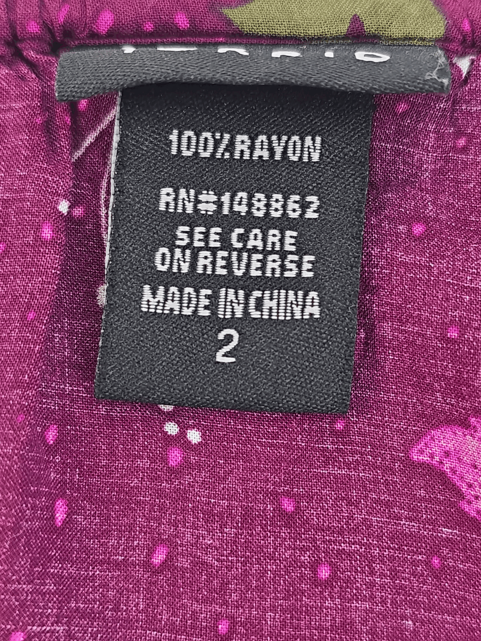 Clothing label with fabric and manufacturing details on a purple garment.