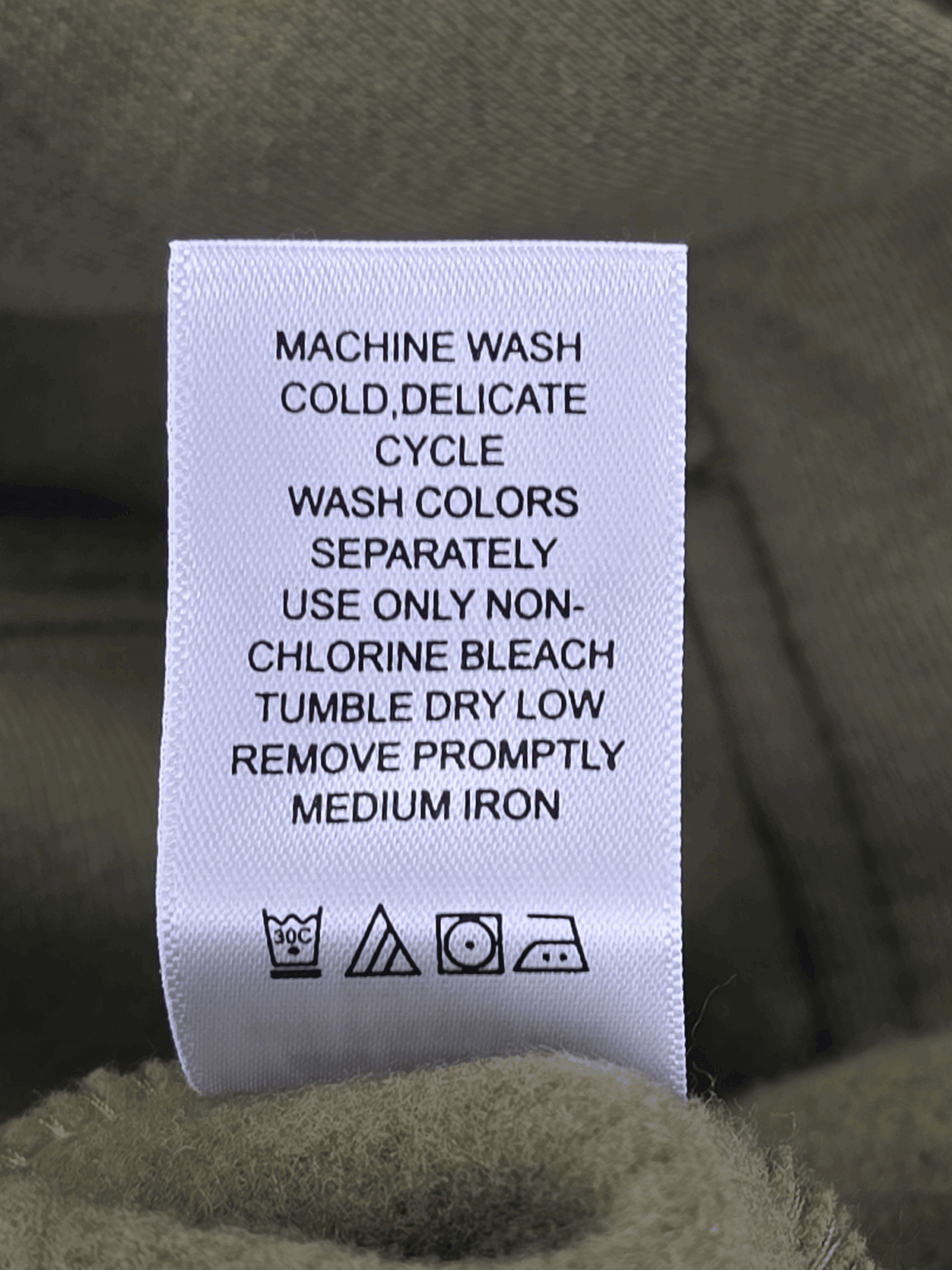 Clothing care label with washing and ironing instructions.