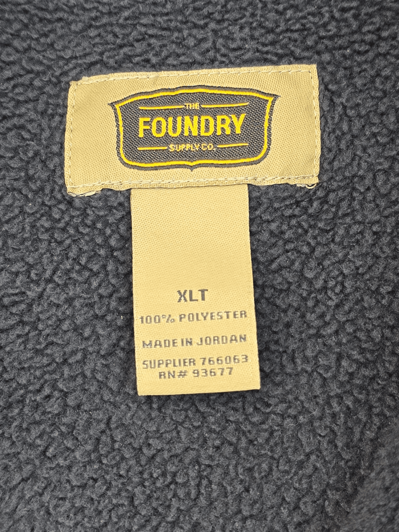 Clothing label with care and manufacturing details on a fabric surface.