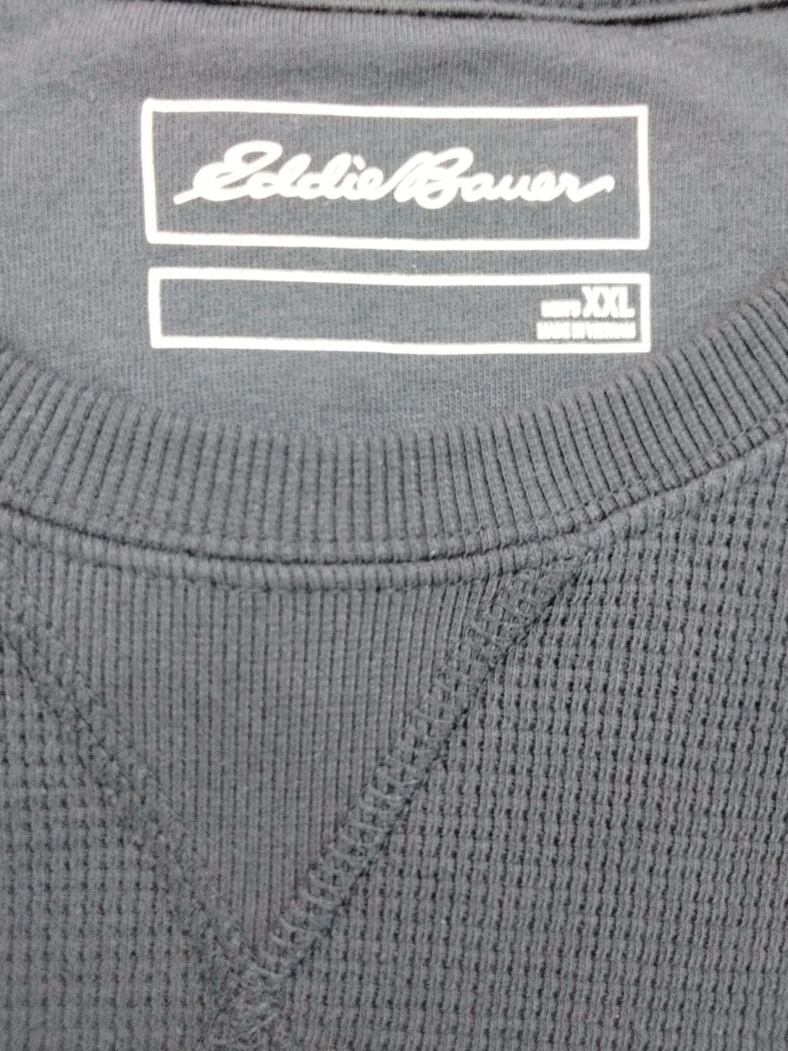 Close-up of an Eddie Bauer black textured sweater label.