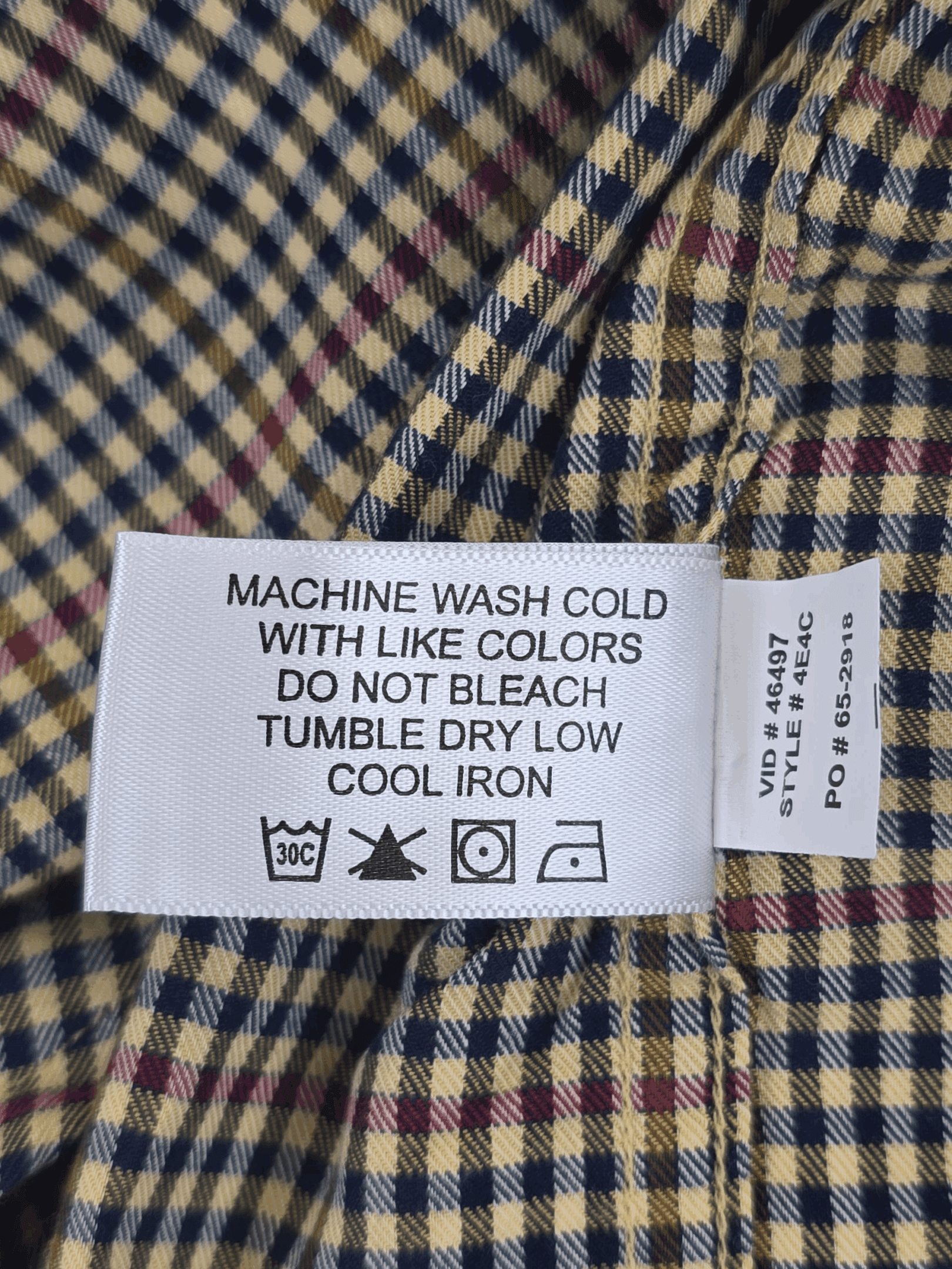 Garment care tag for Orvis red and blue check long sleeve button-up shirt showing washing and drying directions.