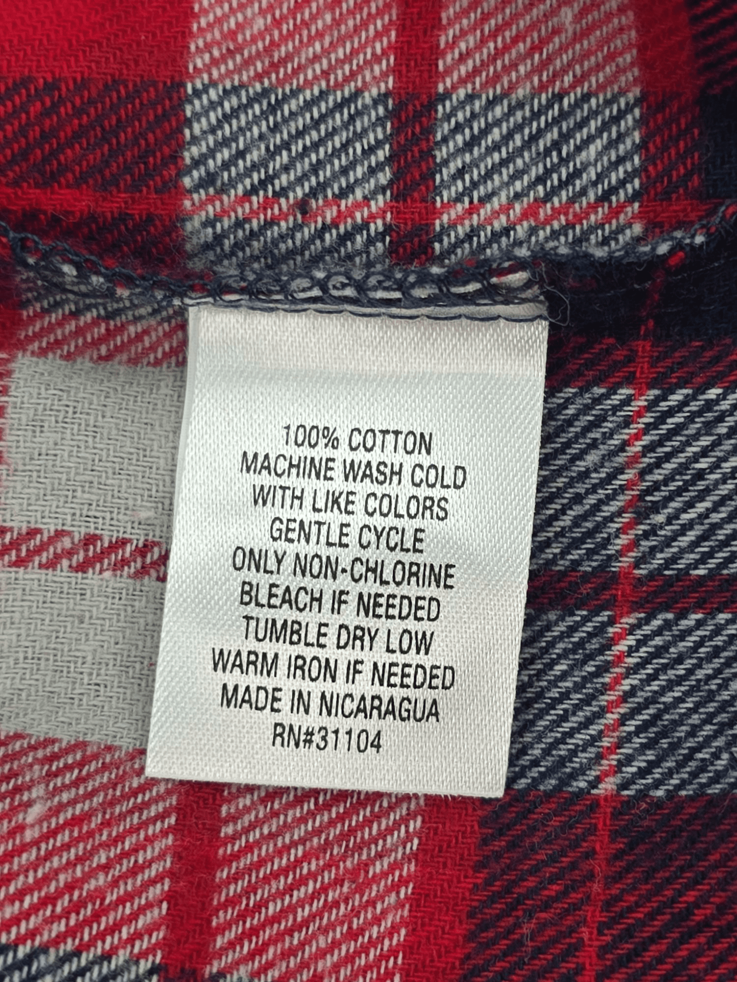 Material content tag listing 100% cotton for Saddlebred Big & Tall red, blue, and gray plaid flannel shirt.