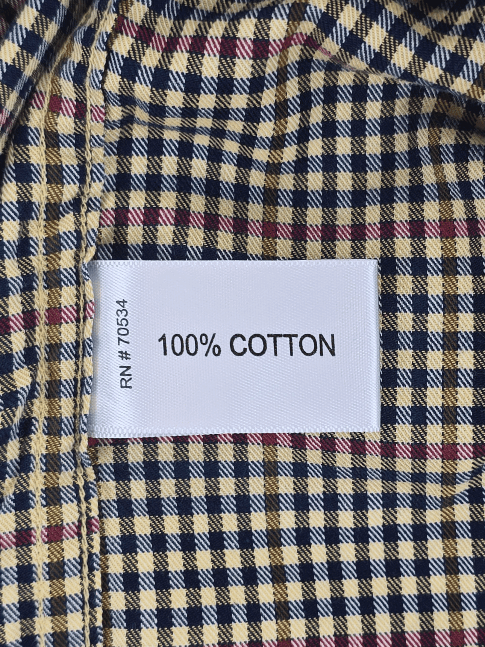 Material content tag listing 100% cotton for Orvis red and blue check long sleeve button-up shirt.