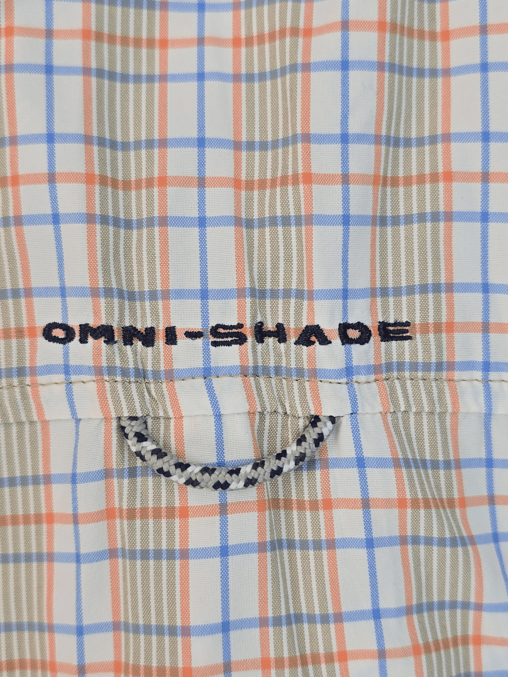 Plaid fabric with "OMNI-SHADE" text and a smiley face design.