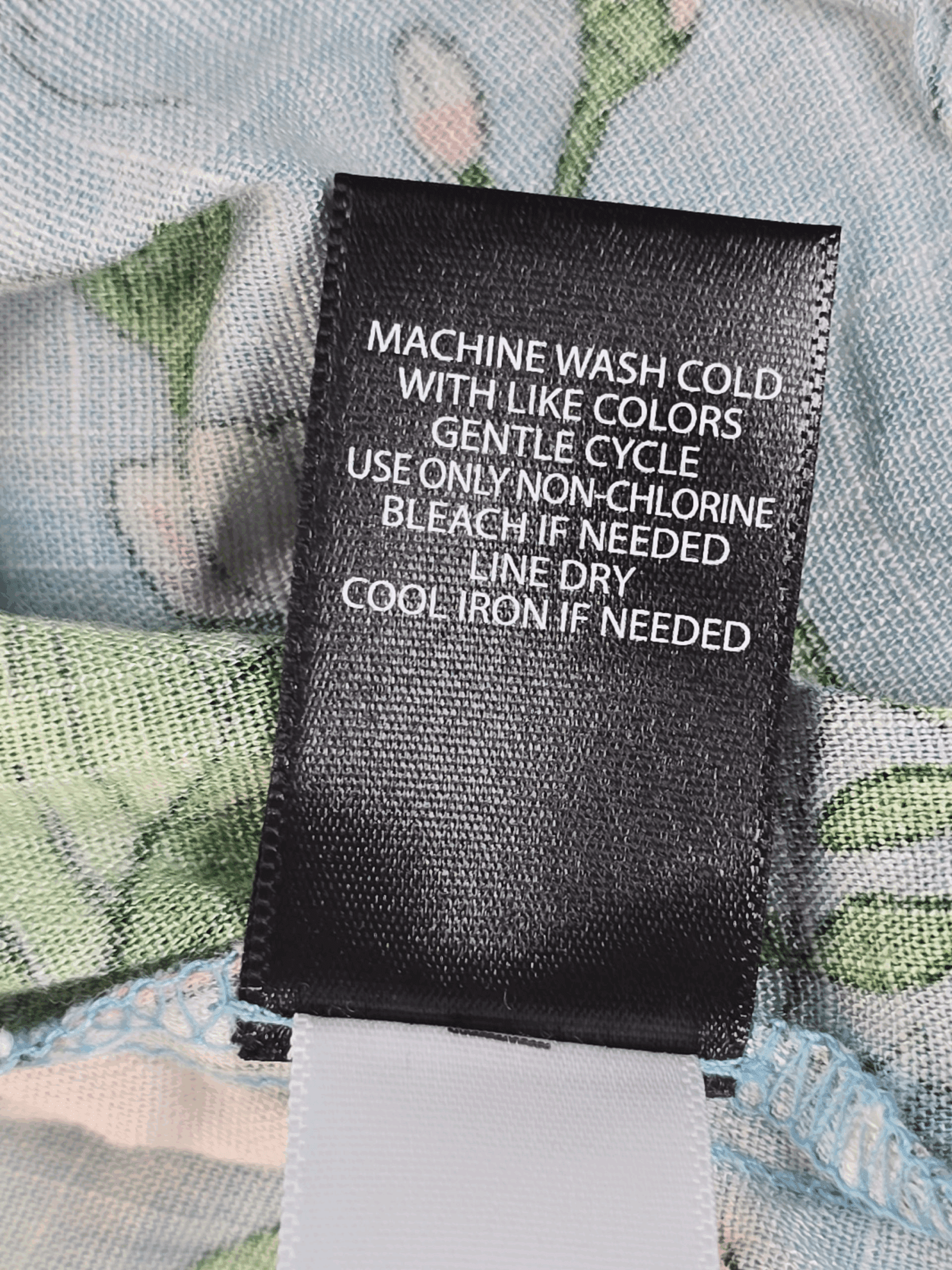 Clothing care label with washing instructions on fabric.