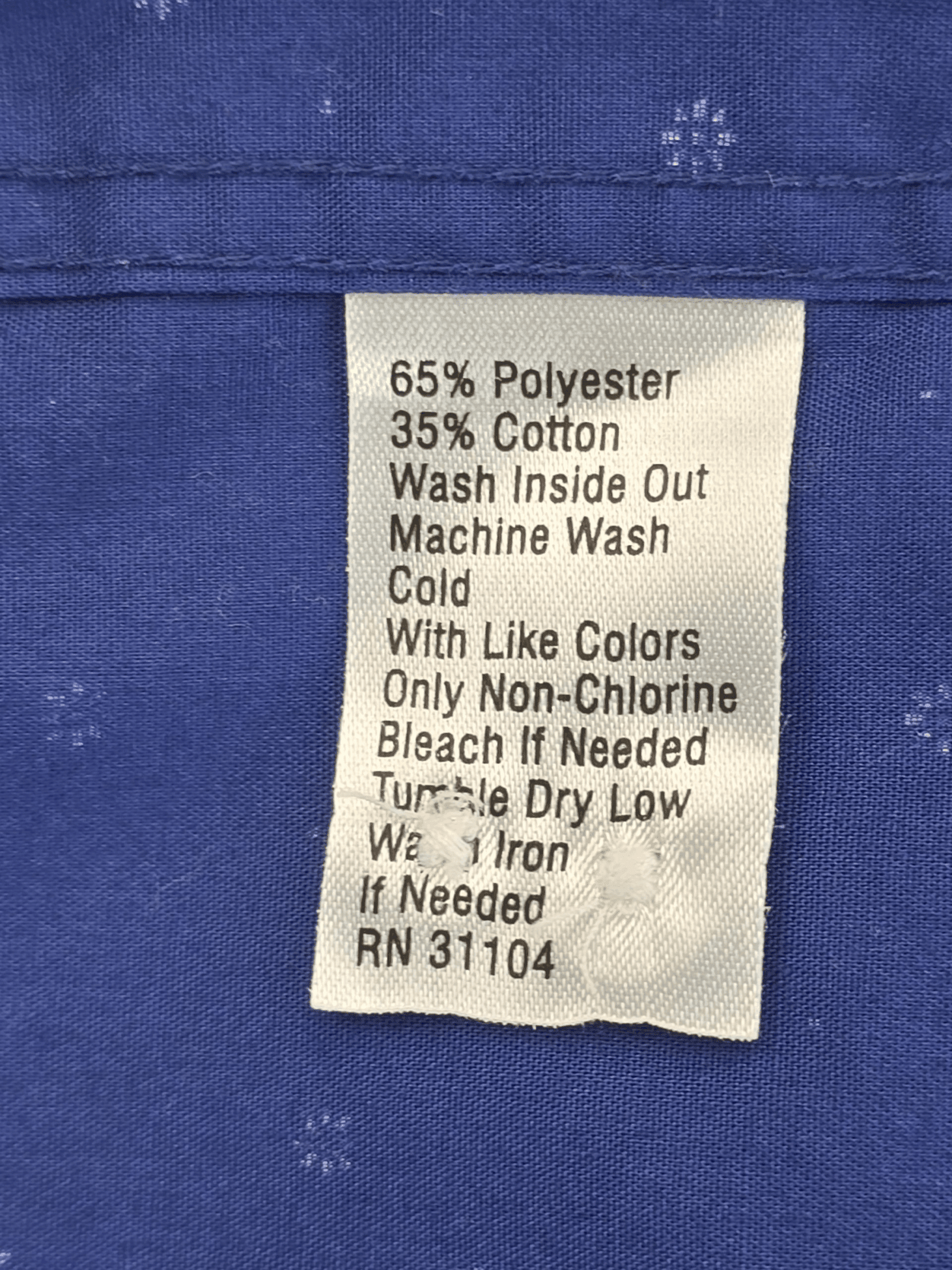 Material content tag listing cotton and polyester blend for Saddlebred blue classic fit short sleeve button-up shirt.