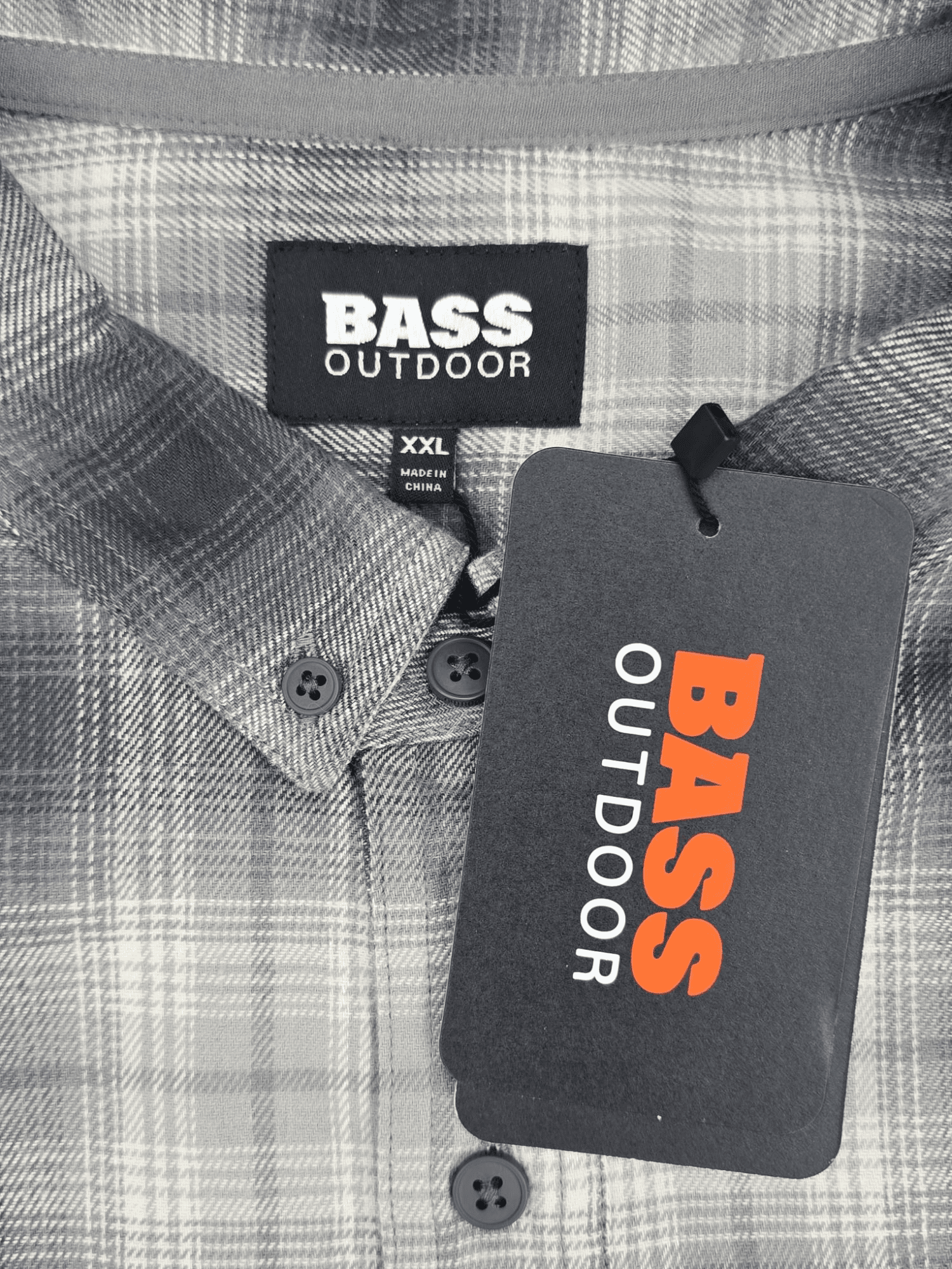Bass Outdoor brand and size tag on gray and white plaid flannel shirt in men’s size 2XL.