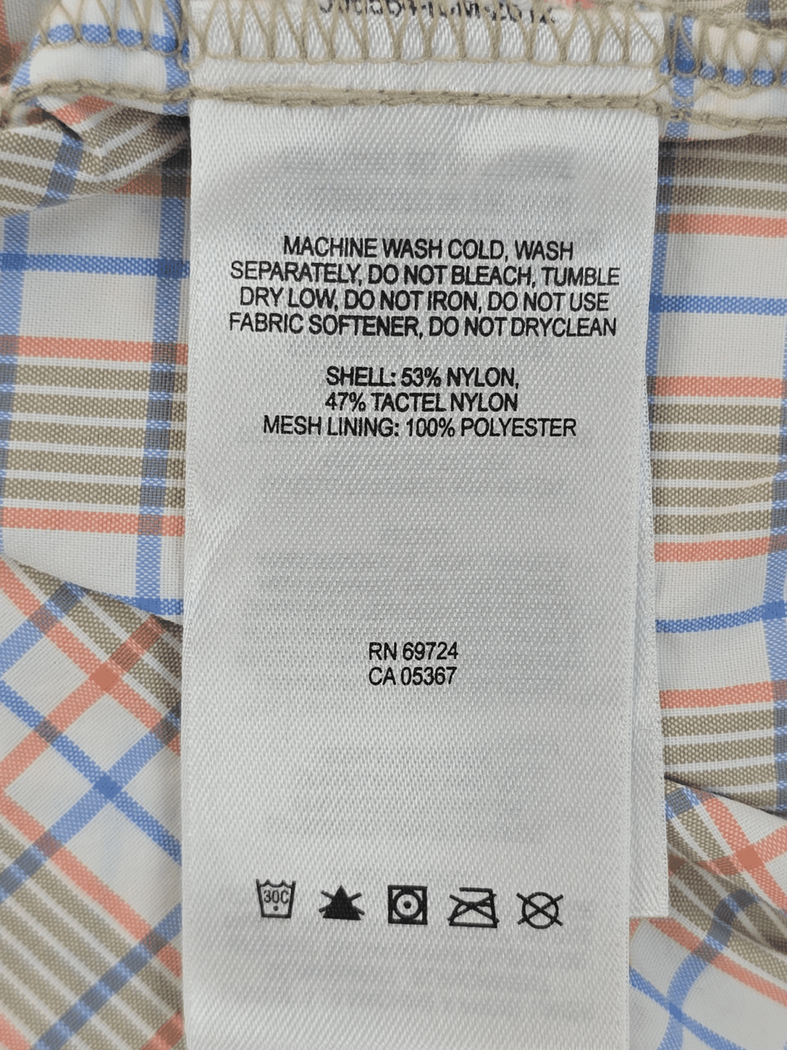 Clothing care label with washing instructions and fabric details.