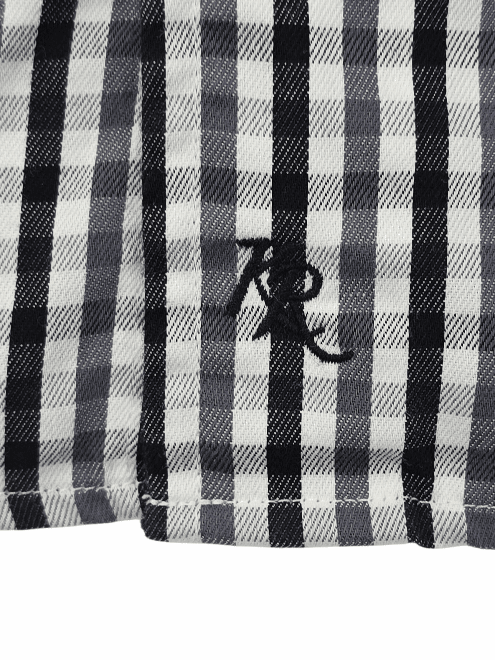 Close-up of black and white checkered fabric with embroidered letters.
