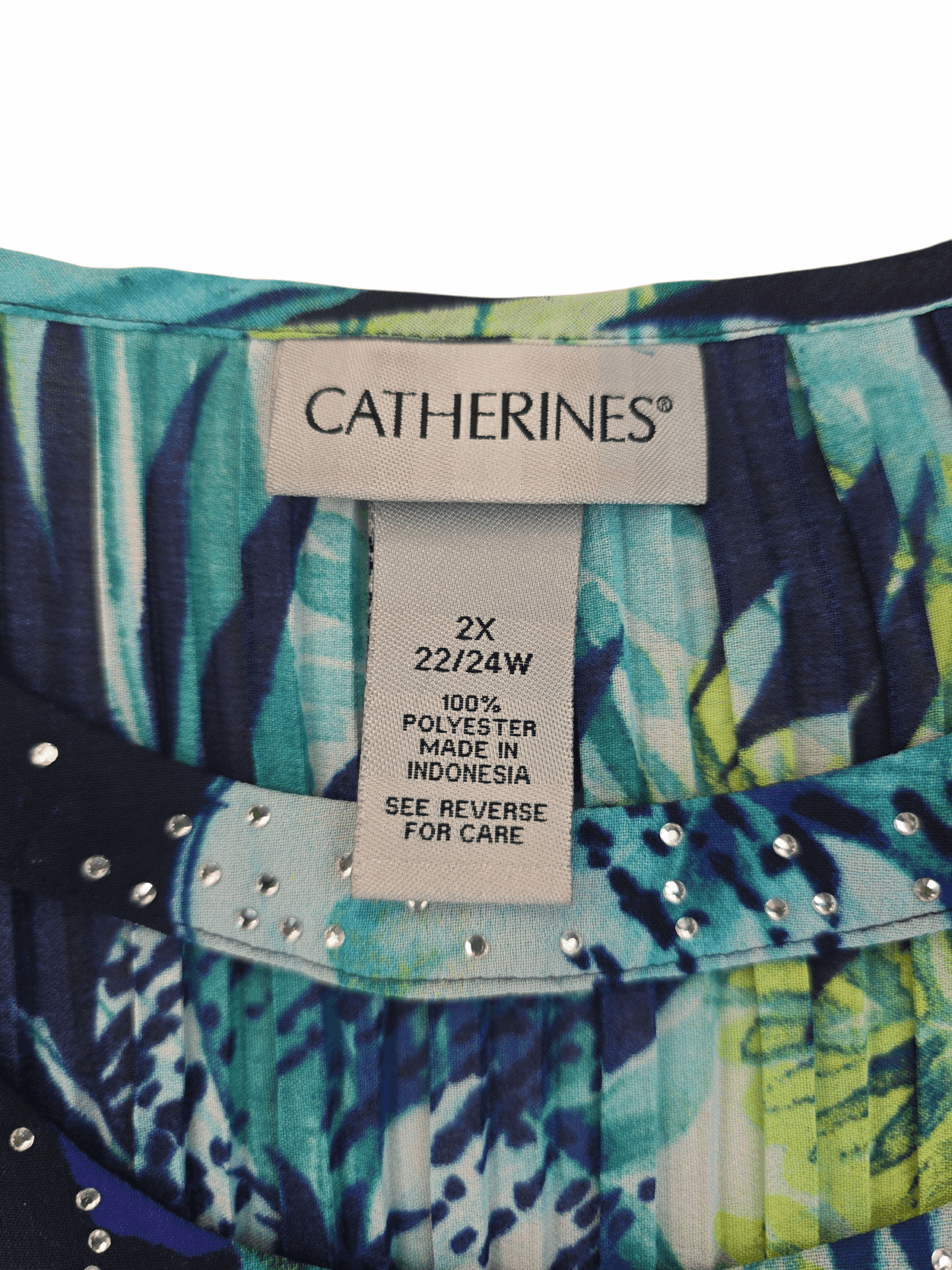Material content tag listing polyester and spandex blend for Catherines blue and green leaf print rhinestone scoop neck top.