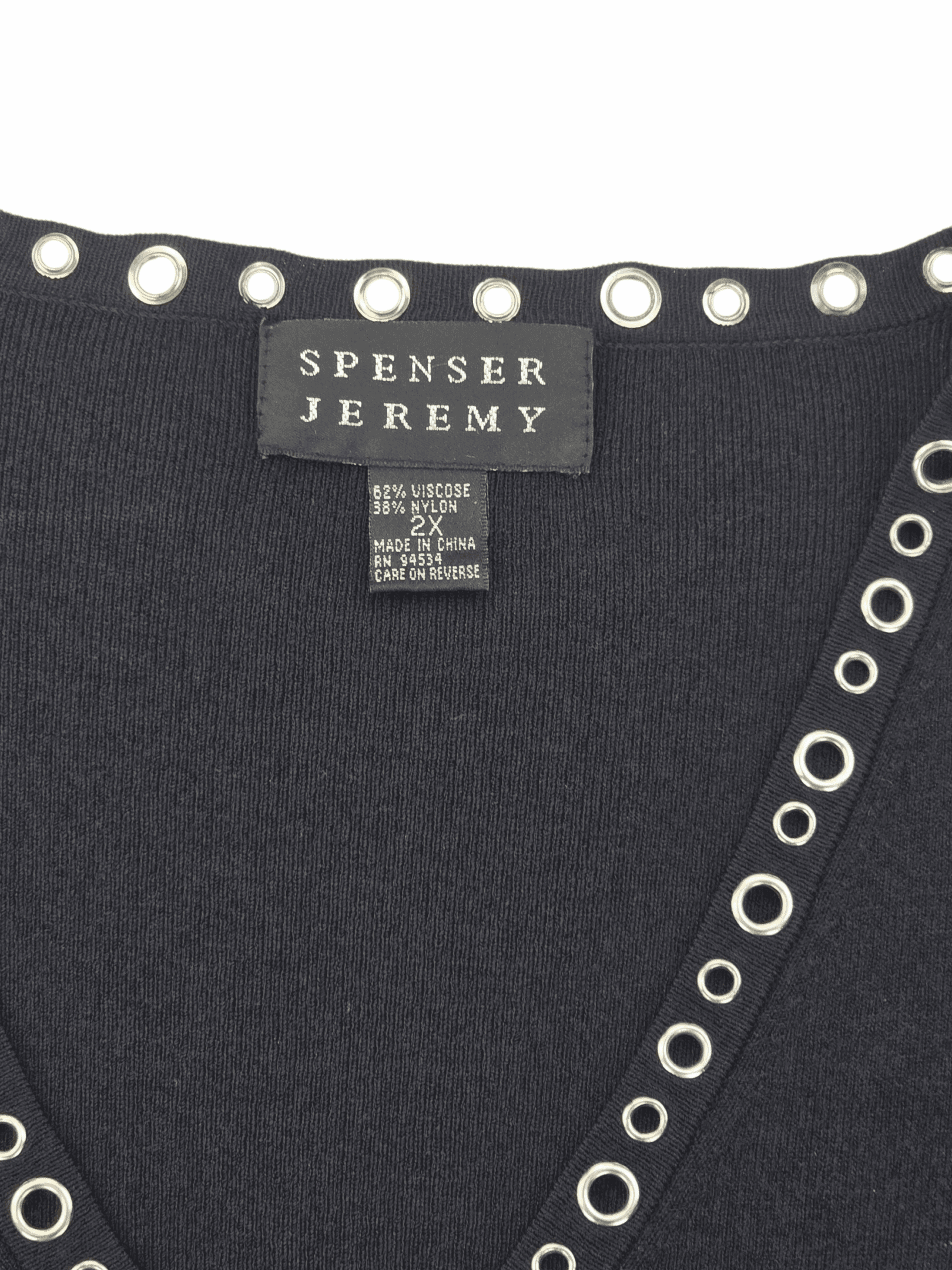 Close-up of a Spenser Jeremy clothing label on a dark garment with grommet details.