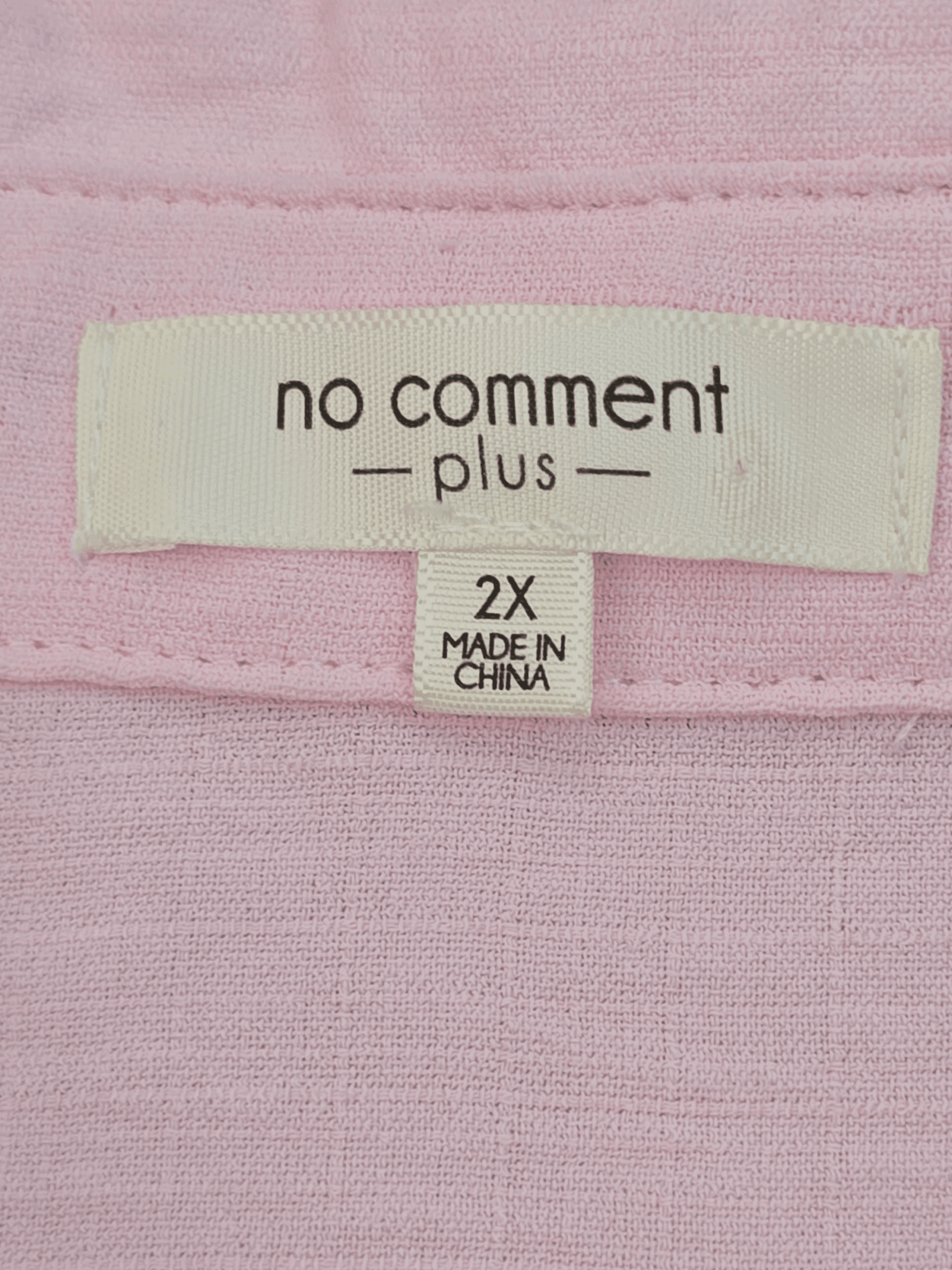 Clothing label showing brand, size, and origin on a pink fabric.