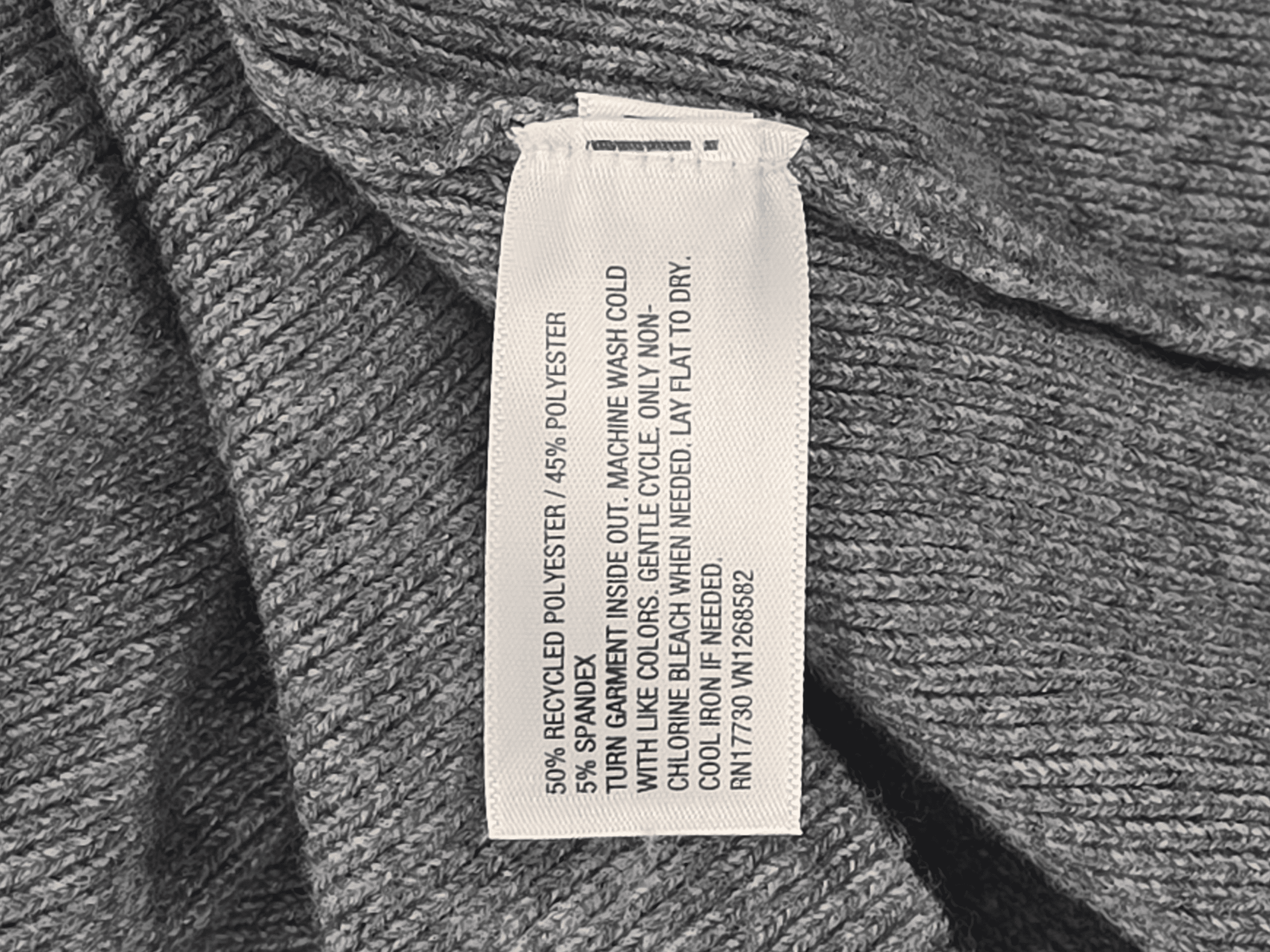 Clothing care label on a grey fabric garment.
