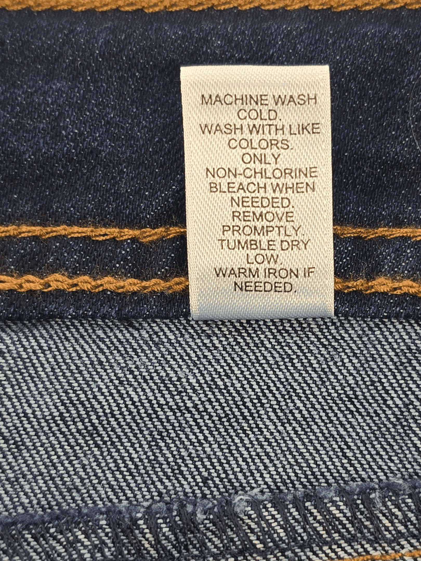 Garment care tag for EST. 1946 denim blue straight-leg jeans showing washing and drying directions.