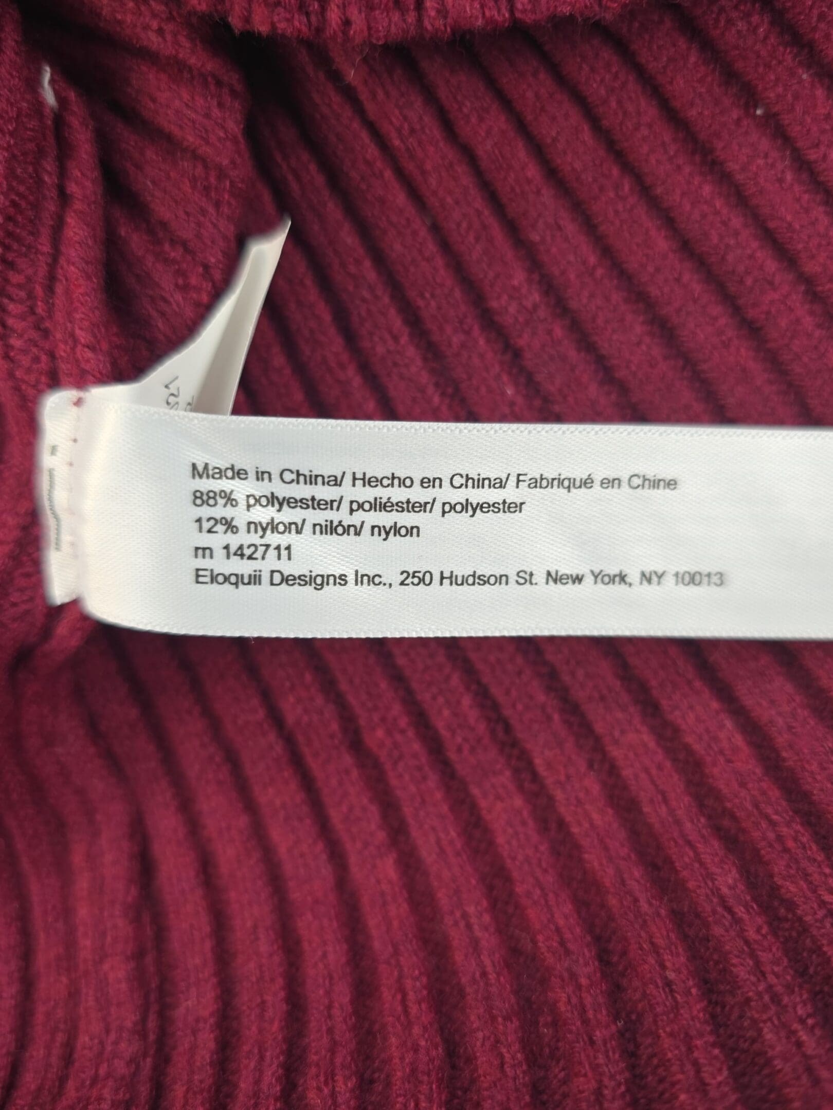 Clothing tag with fabric and care information on a red garment.