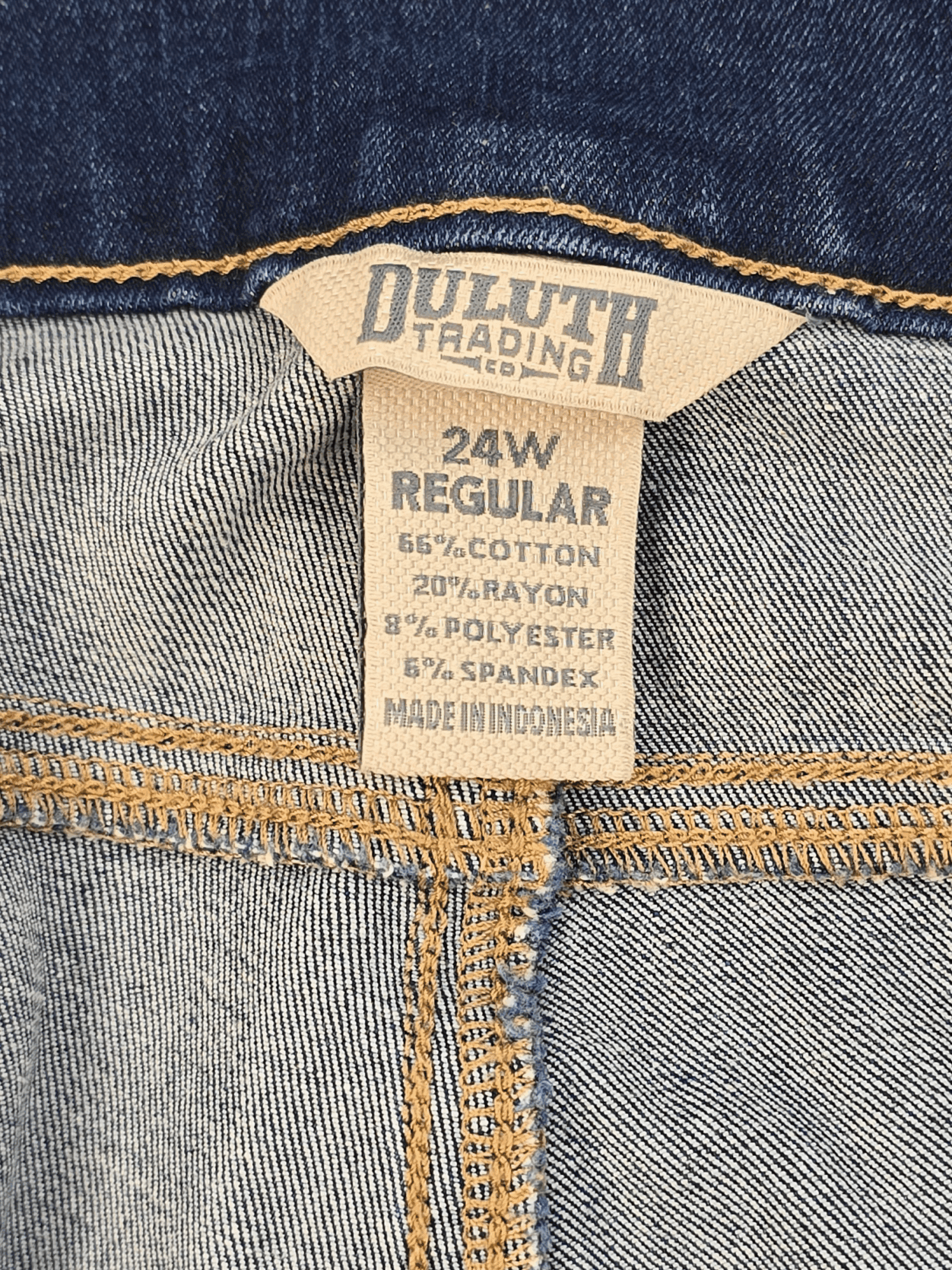 Close-up of Duluth brand and 24W Regular size tag on blue pull-on skinny jeans