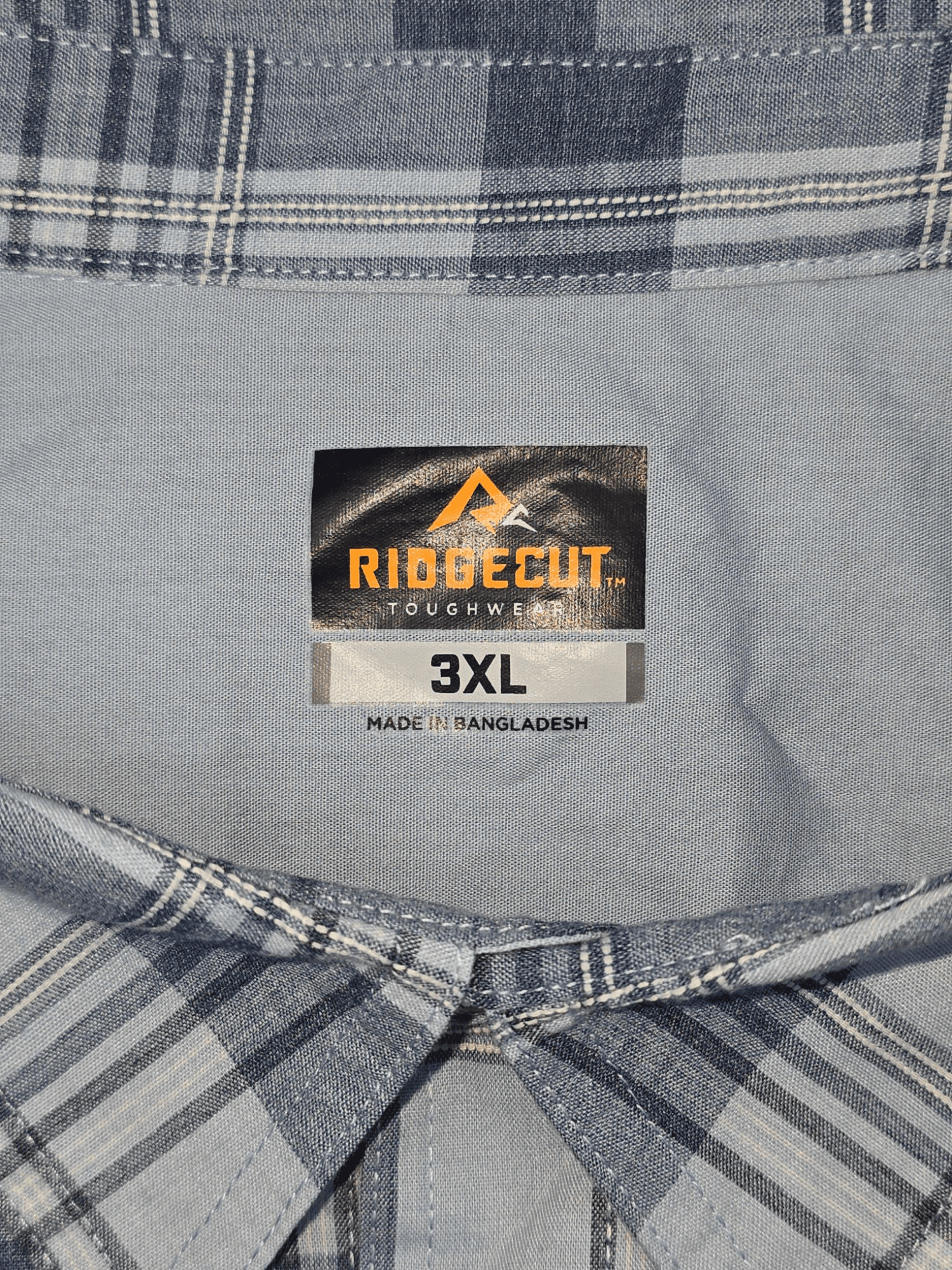 Close-up of Ridgecut brand and 3XL size tag on blue checked button-up shirt