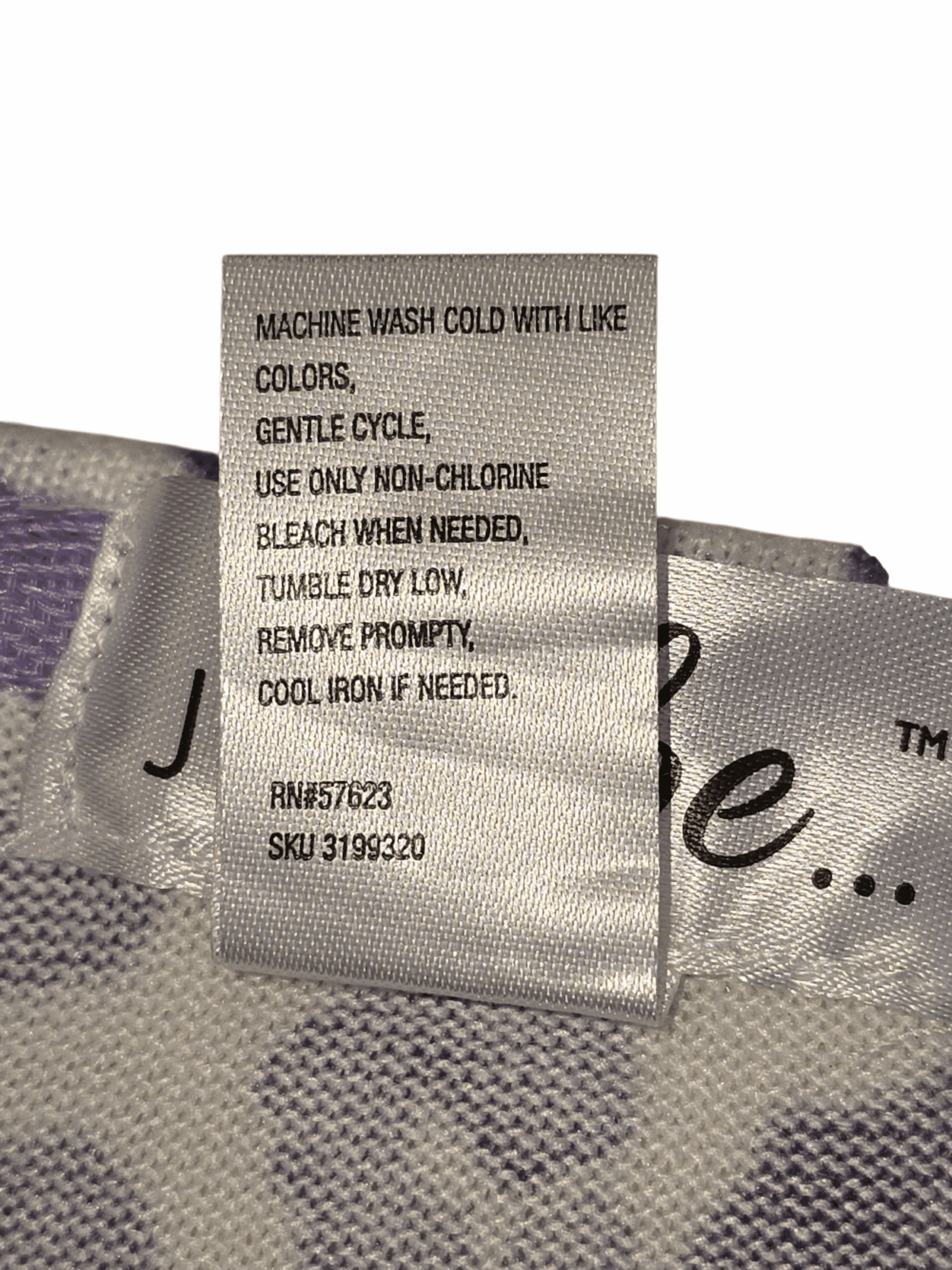 Close-up of material content and garment care tag on Just Be women’s 3X purple and white animal print sweater
